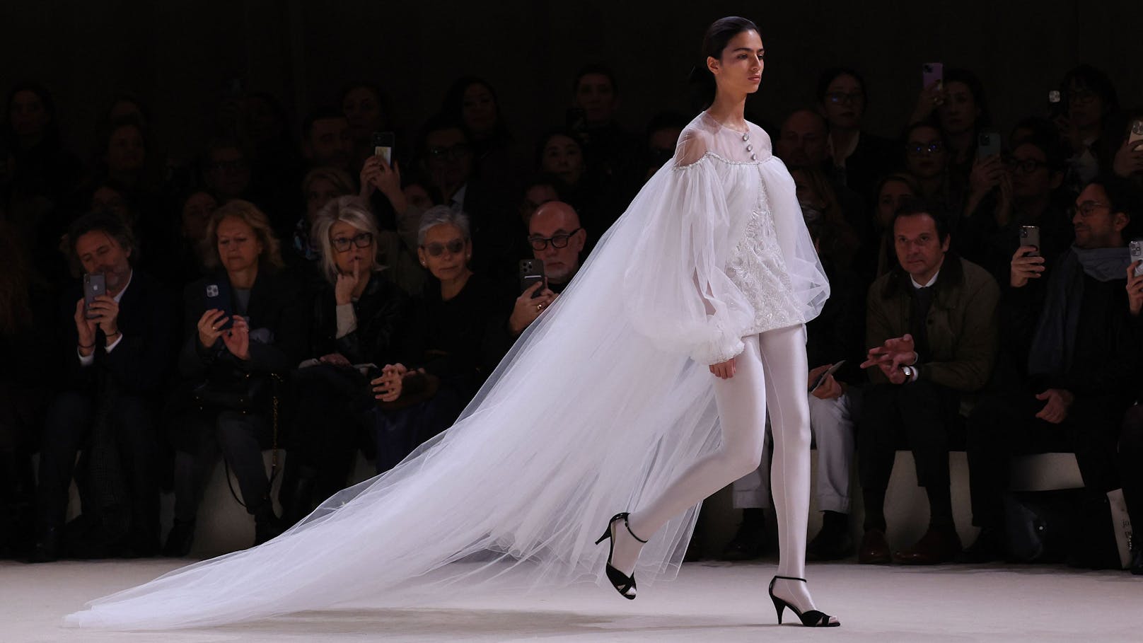 Der voluminöse Tüll endet bei den Hüften, darunter trägt die Chanel-Braut 2024 statt einer Hose oder einen Rock, lediglich eine weiße, blickdichte Strumpfhose.