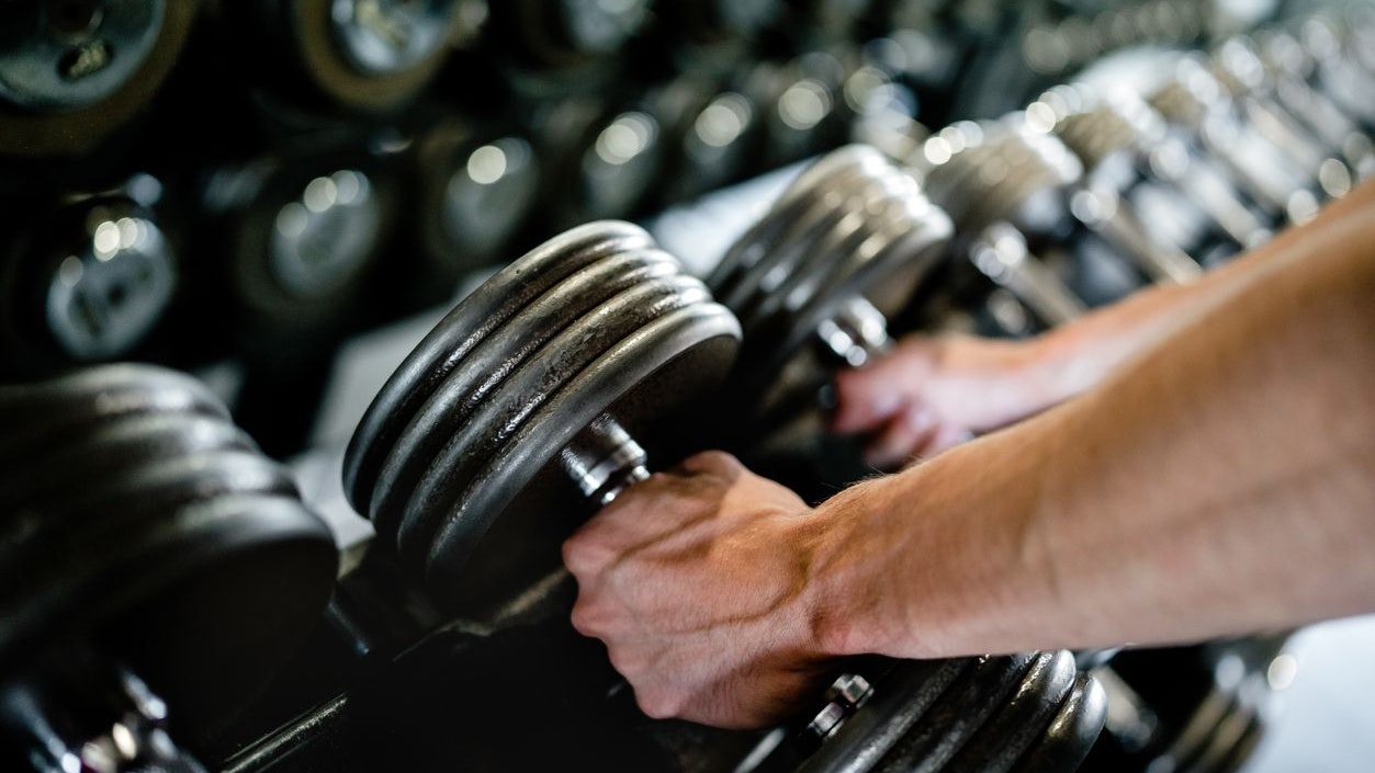 Close-up of muscular hands picking up dumbbells in the gym