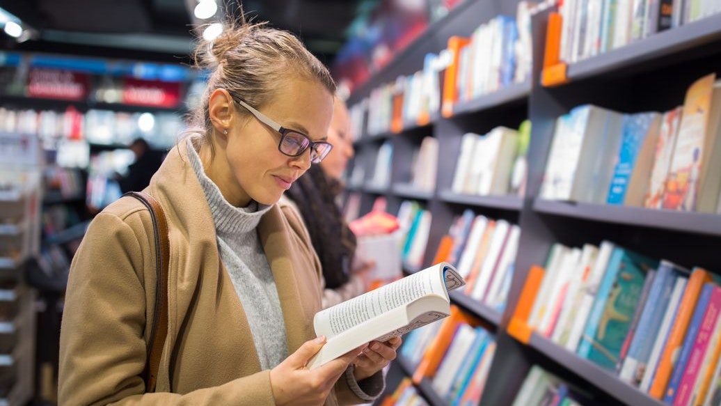 Pretty, young female choosing a good book to buy in a bookstore