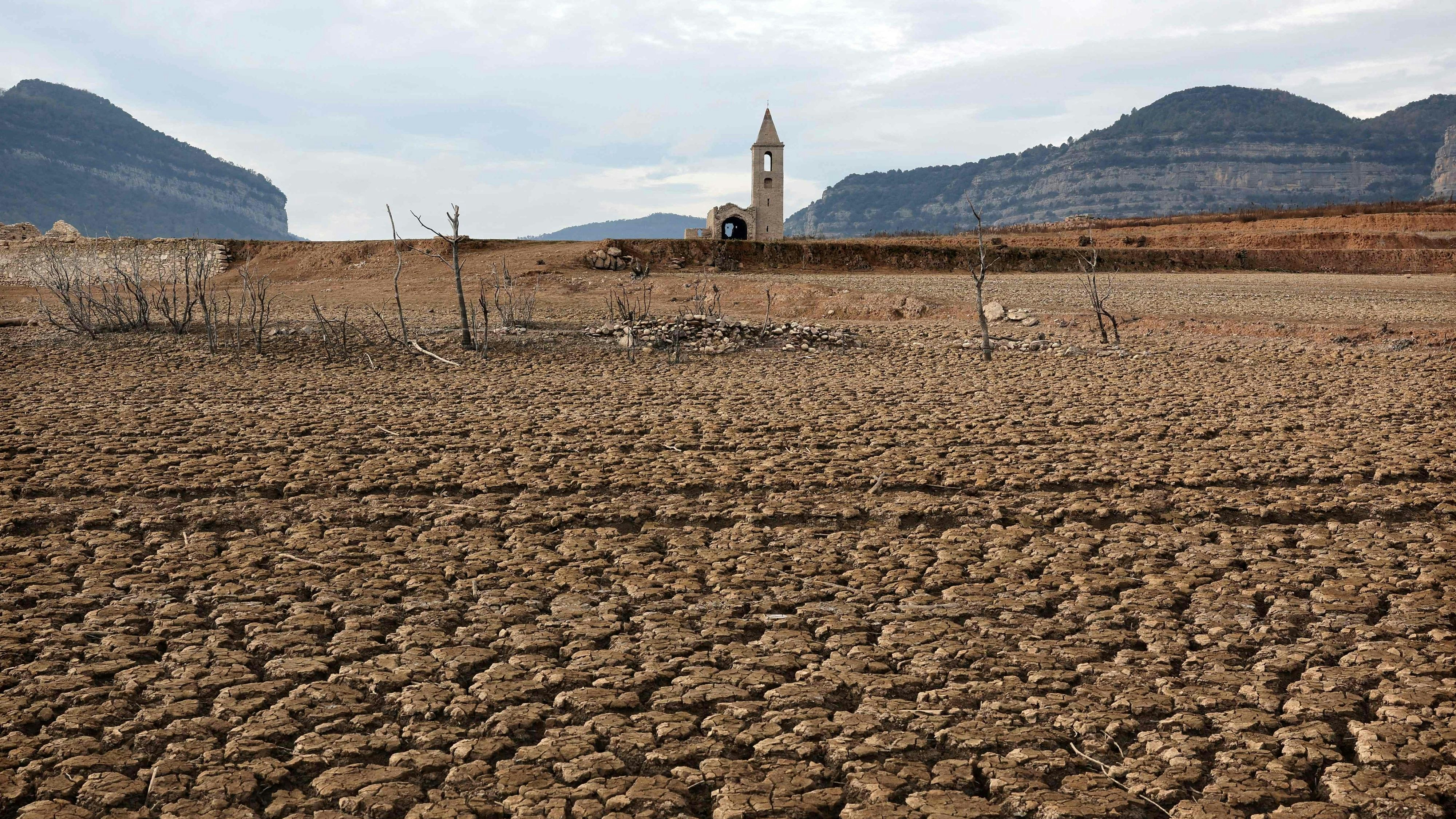 Download von www.picturedesk.com am 25.01.2024 (12:34).  TOPSHOT - This photograph taken on January 15, 2024 shows the dry soil next to the low water-level reservoir of Sau with in background Sant Roma de Sau church, in the province of Girona in Catalonia. Catalonia struggles with historic drought for three years, with some residents already experiencing water restrictions in their daily life. (Photo by LLUIS GENE / AFP) - 20240116_PD20590 - Rechteinfo: Rights Managed (RM) Nur für redaktionelle Nutzung! Werbliche Nutzung erfordert Freigabe: bitte schicken Sie uns eine Anfrage.