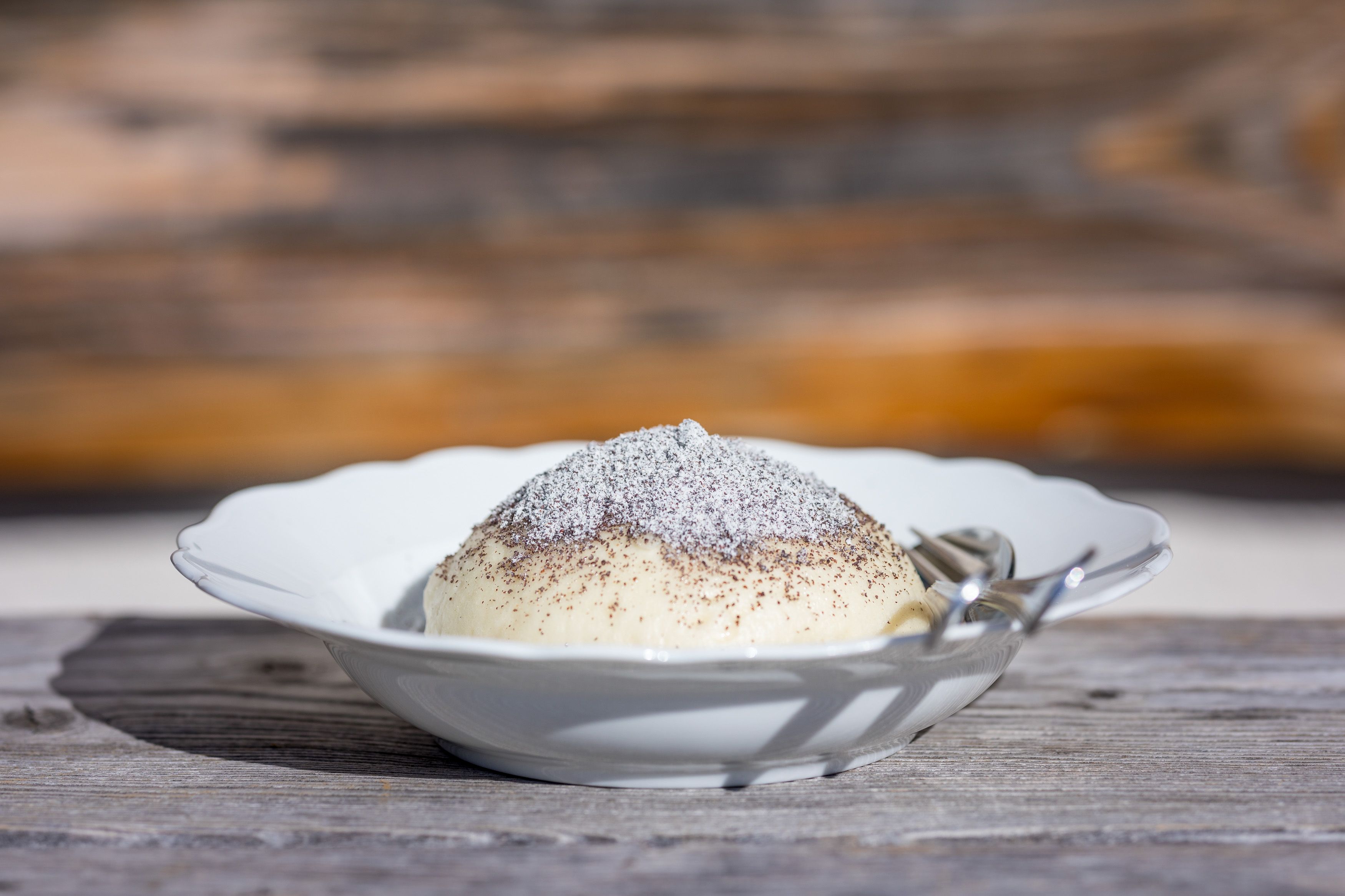 Germknödel mit Vanillesauce, Mohn und Staubzucker zählt zu den beliebtesten Süßspeisen in den Skihütten Österreichs.