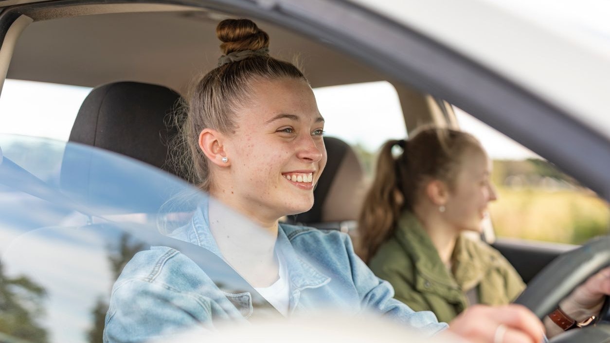 Proud Young Woman Driving Friends in Her First Car