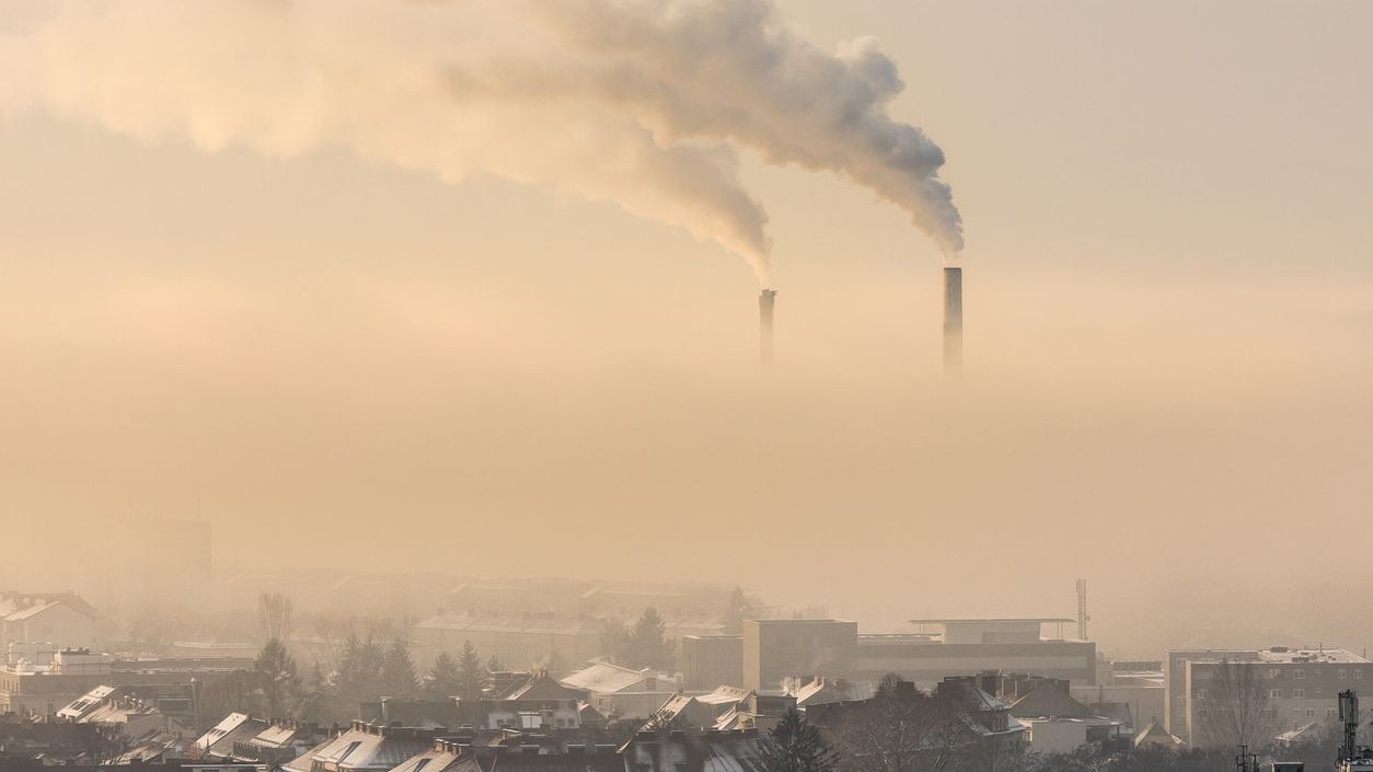 Smoking industrial chimneys emitting fine dust and carbon dioxide over Graz in Austria on a foggy winter morning