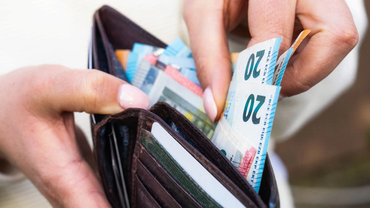 Macro image as a woman takes Euro banknotes from a leather wallet.
