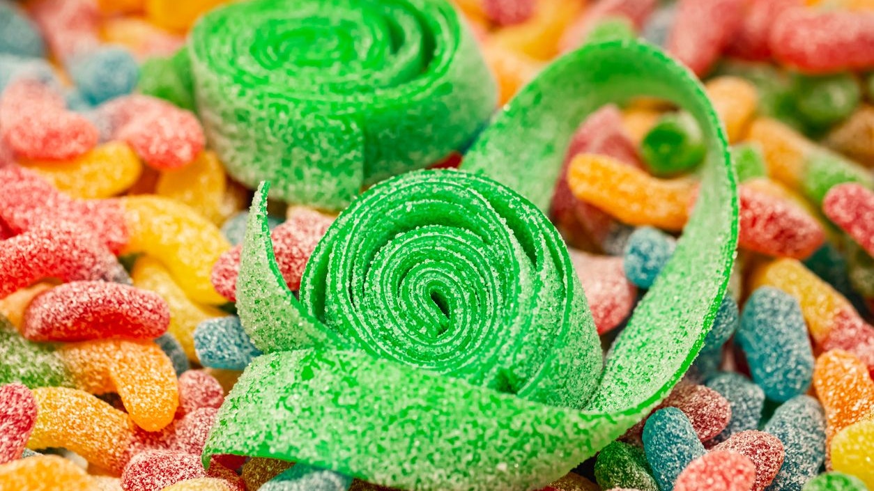 Close-up, background with green rolled gummies coated with sugar, macro shot.