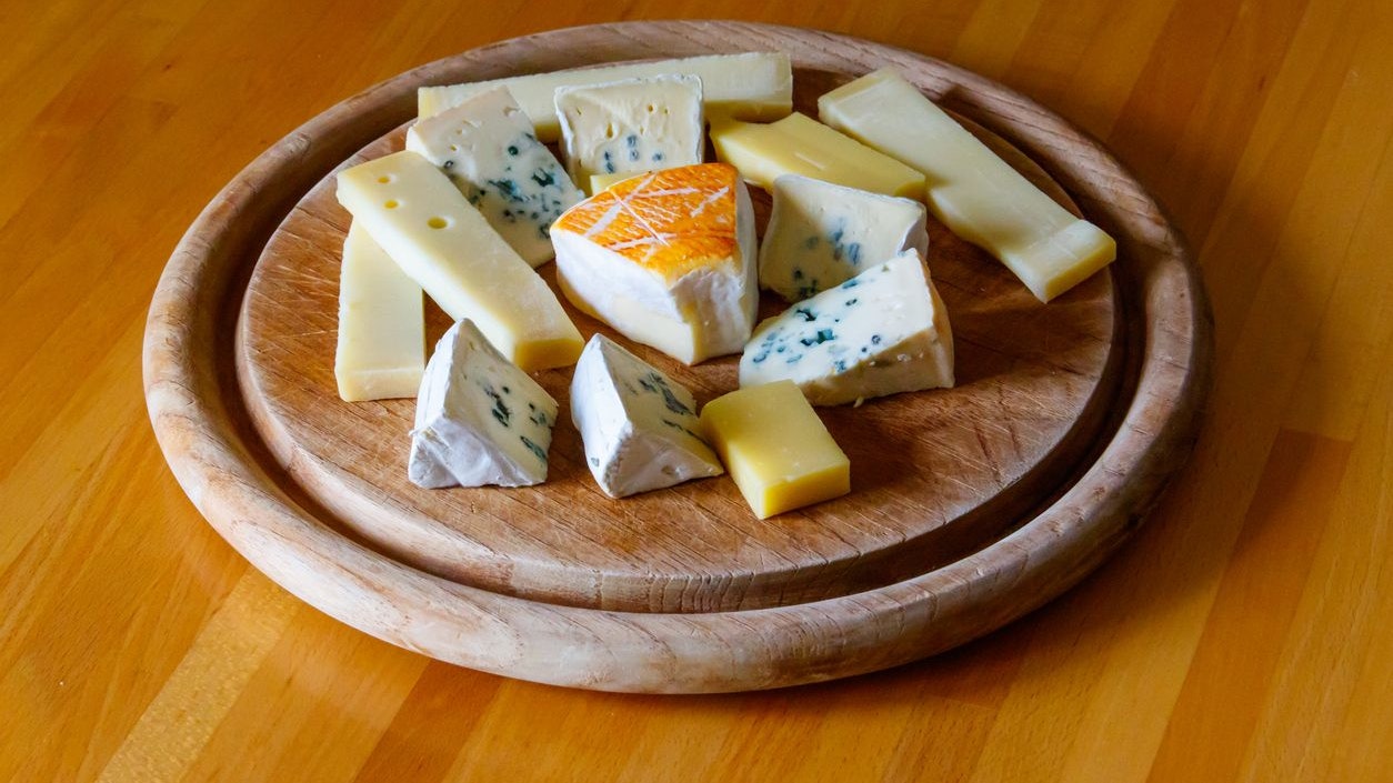 Cheese platter with different kinds of cheese on wooden table