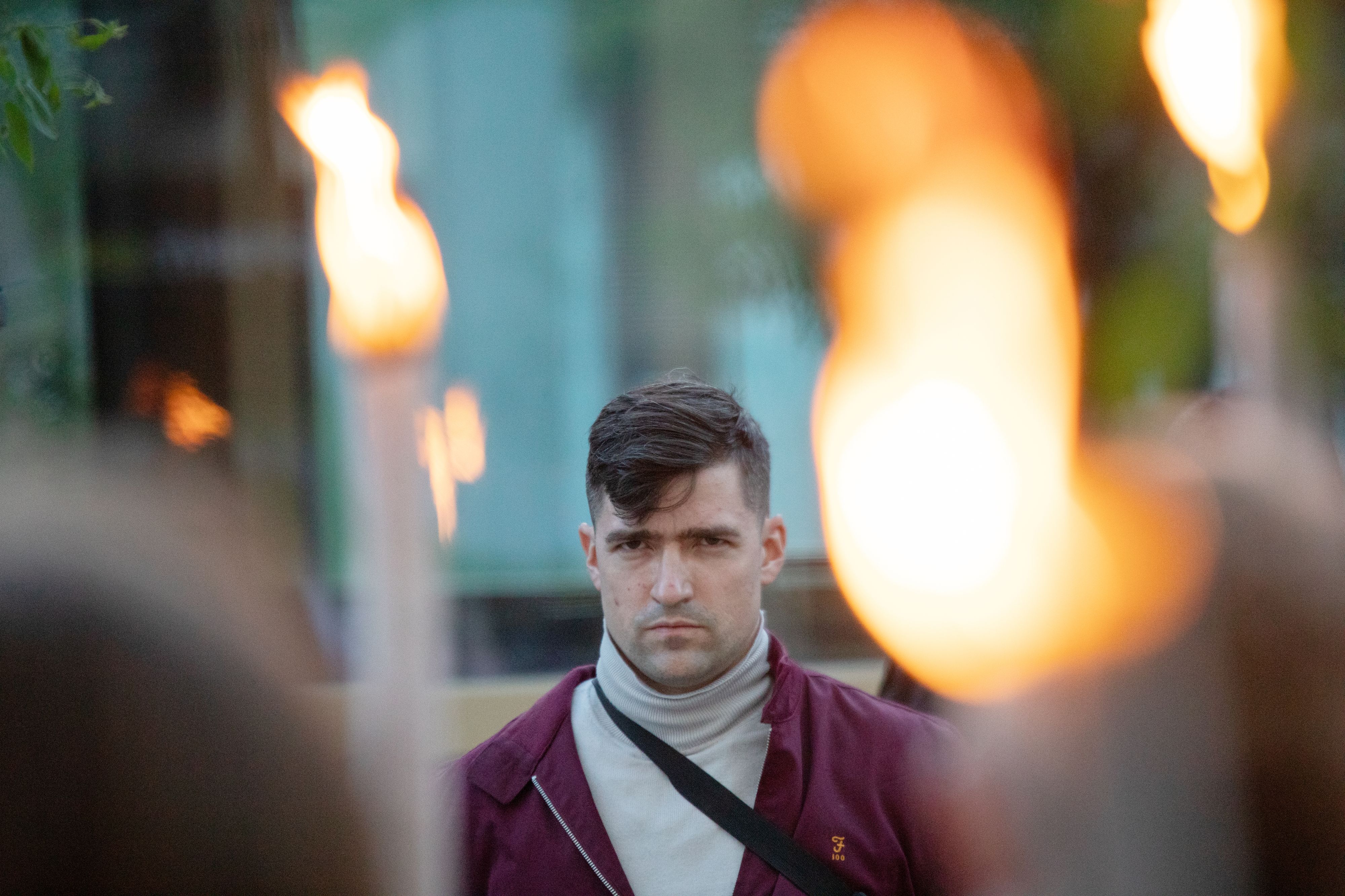 Sprecher der Identitären Bewegung Österreich (IBÖ) Martin Sellner zwischen brennenden Fackeln während eines Auftritts am Brunnenmarkt in Wien 2021.