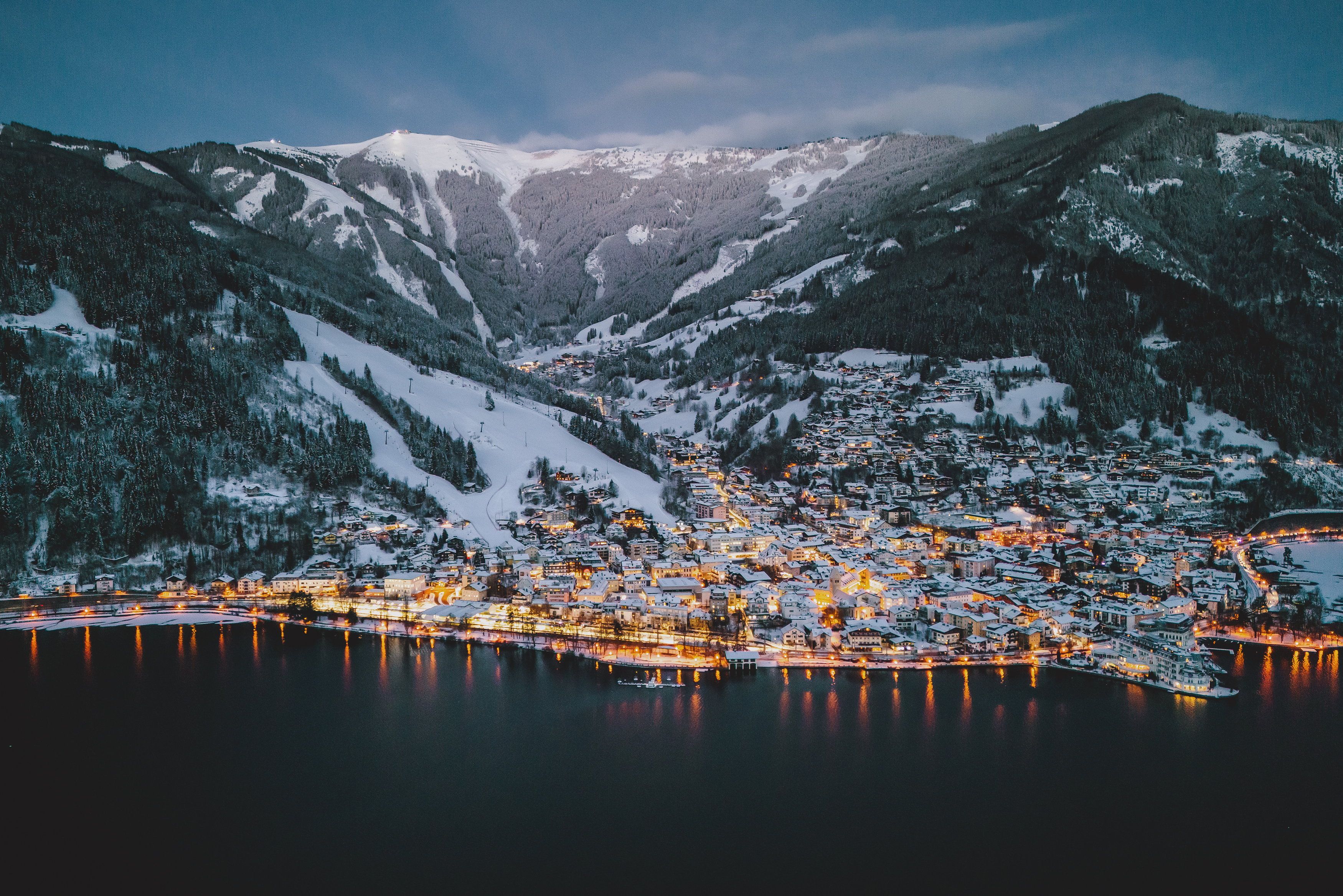 Beleuchtete Stadtansicht mit dem Zeller See und der Schmitten im Morgengrauen, aufgenommen am 16. Jänner 2024 in Zell am See.