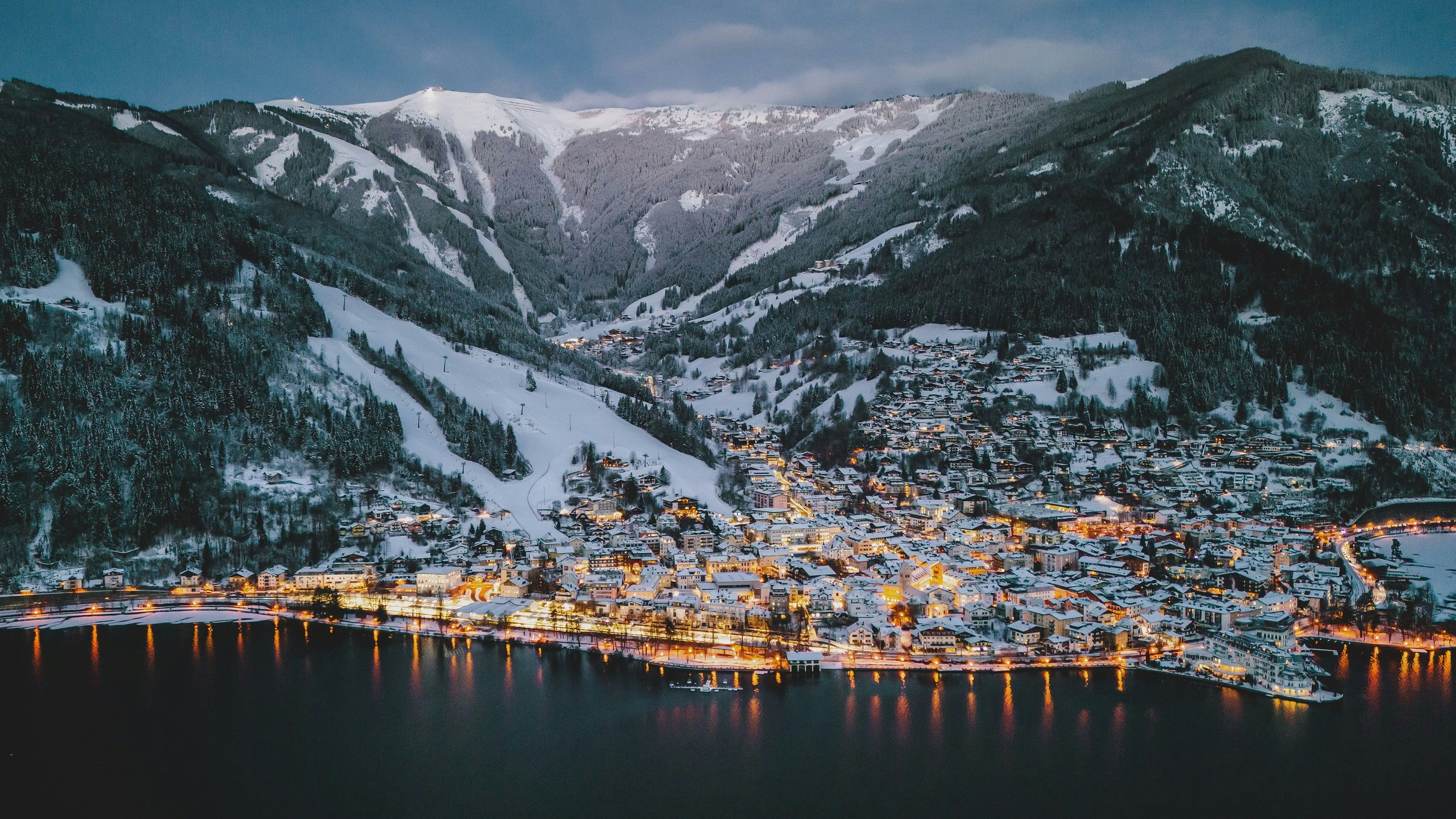 Beleuchtete Stadtansicht mit dem Zeller See und der Schmitten im Morgengrauen, aufgenommen am 16. Jänner 2024 in Zell am See.