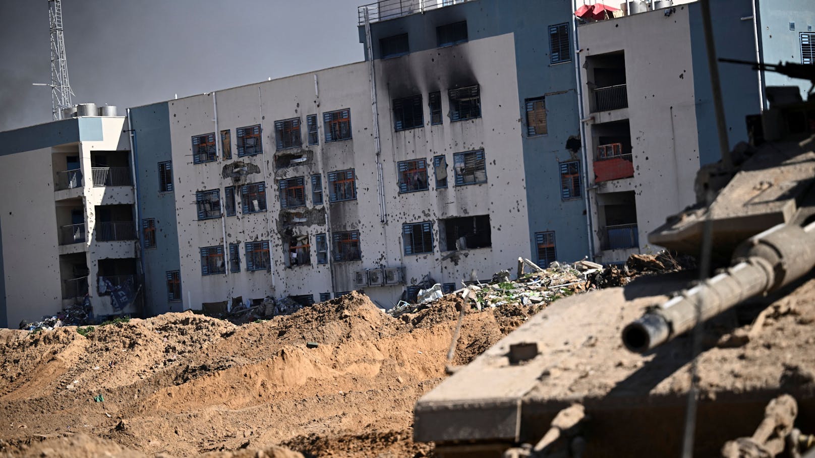 Ein israelischer Panzer vor einem mit Schüssen durchlöcherten Haus im Gazastreifen.