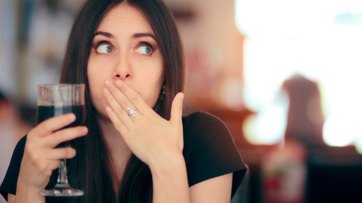 Woman covering her moth after drinking cola