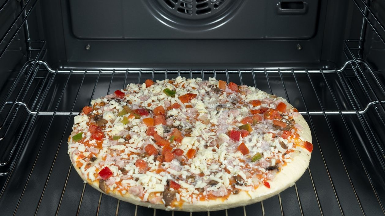 Raw and frozen pizza in the oven.