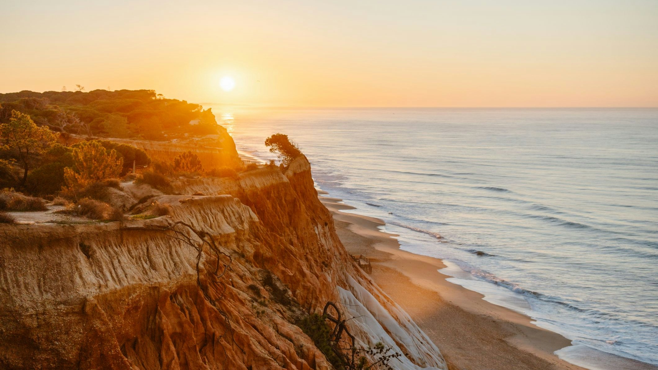 Goldener Sand und rote Klippen prägen den Falésia Beach an der Algarve.