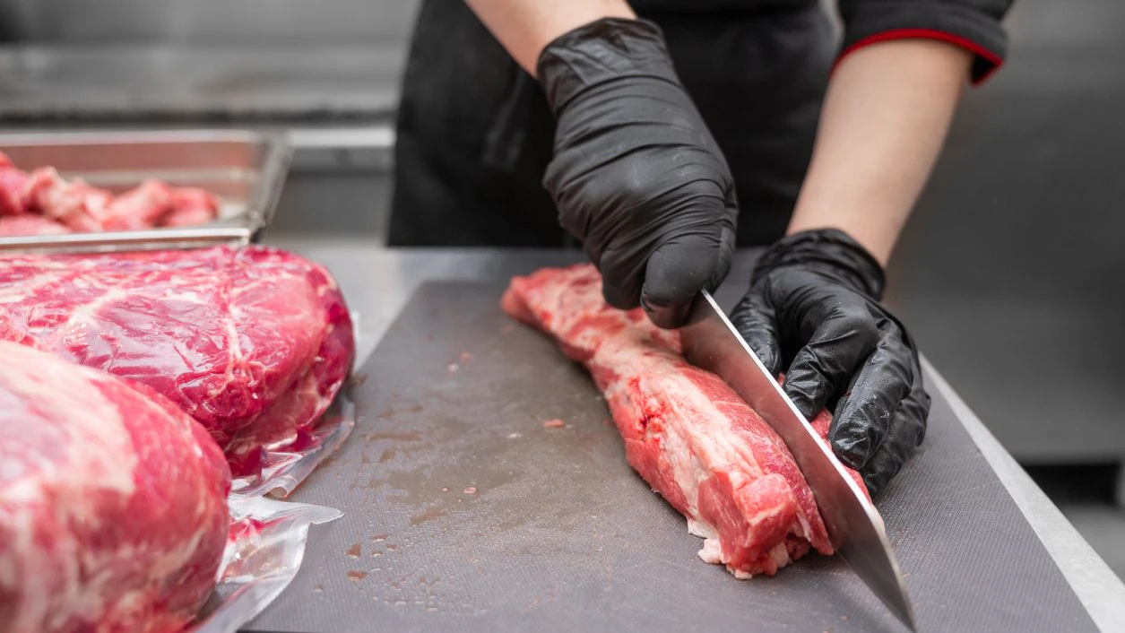 Close up of raw meat and woman butcher cutting meat with knife. High quality photo