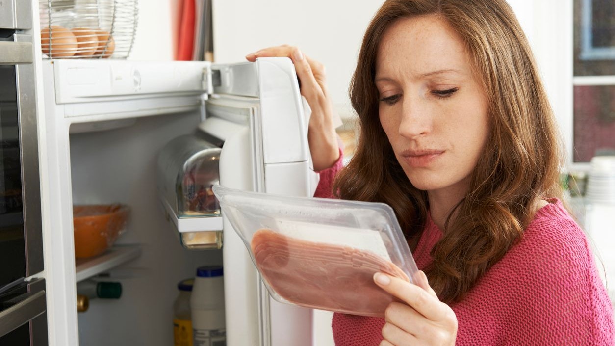 Concerned Woman Looking At Pre Packaged Meat