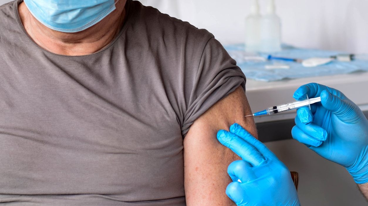 Elderly man in a medical office getting ready for vaccination. Portrait of senior man wearing medical medicine mask for Covid-19 Flu Protection. Old man in Clinic during Covid-19, coronavirus pandemic