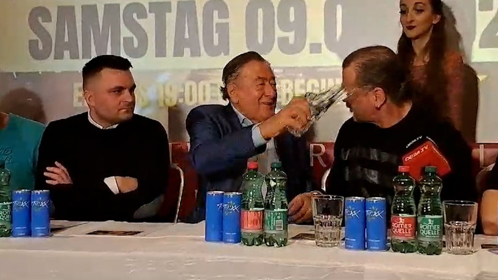 Lugner schüttet ein Glas Wasser dem vorlauten Wrestler Kovac ins Gesicht.