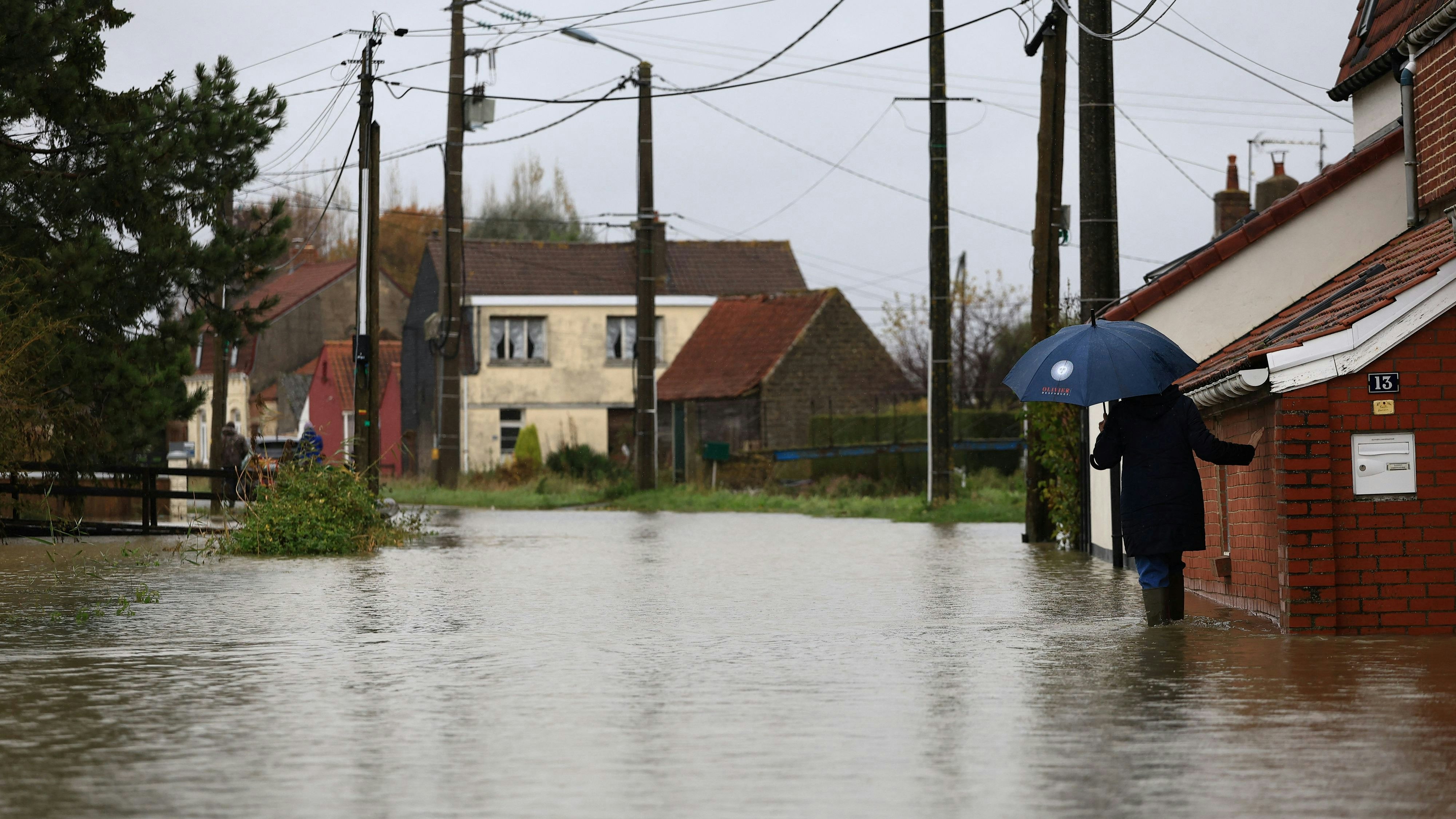 A woman walks in a flooded street of Le Doulac, northern France, Tuesday, Nov. 14, 2023. President Macron and his wife, Brigitte, visit inundated towns near Calais in northern France after a series of storms and heavy rains forced school evacuations, flooded farm fields and strained public services. Macron wants to show his support to residents and rescue teams, the French presidency said.     Aurelien Morissard/Pool via REUTERS