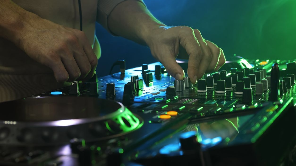DJ creating music on modern console mixer in night club, closeup
