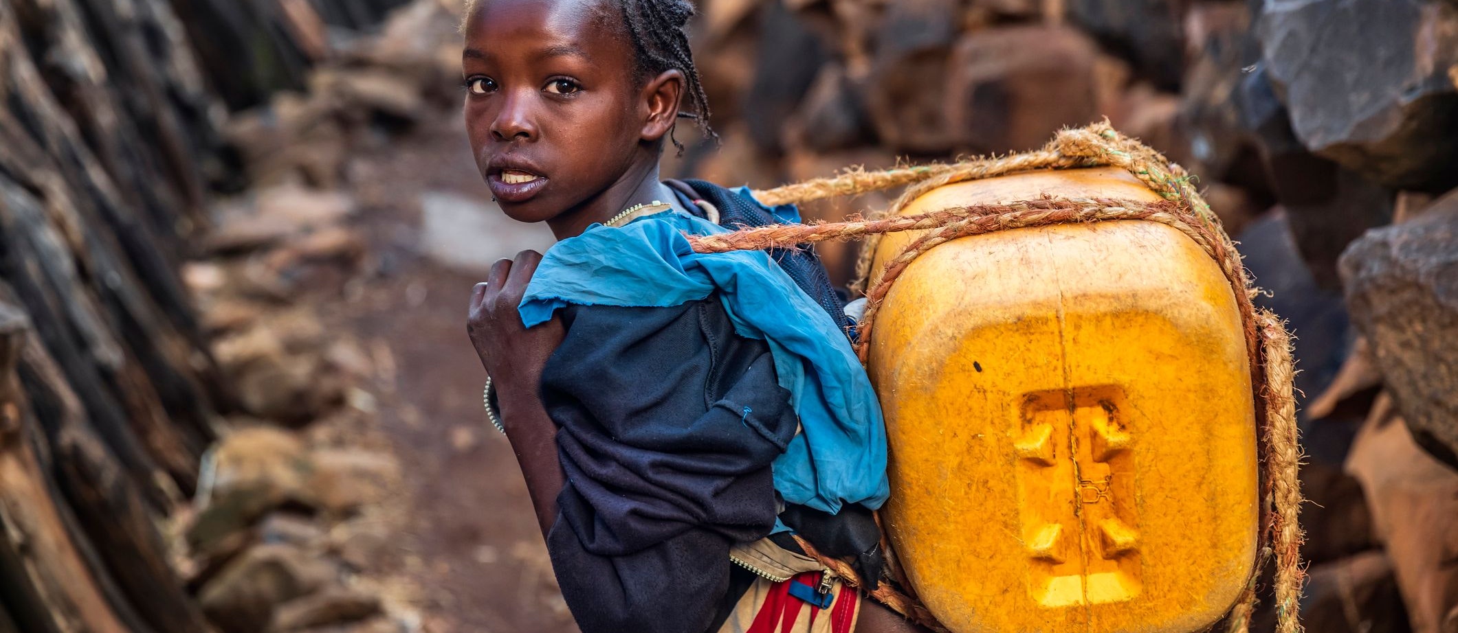 Ein Mädchen trägt in Äthiopien einen Kanister mit Wasser heim 