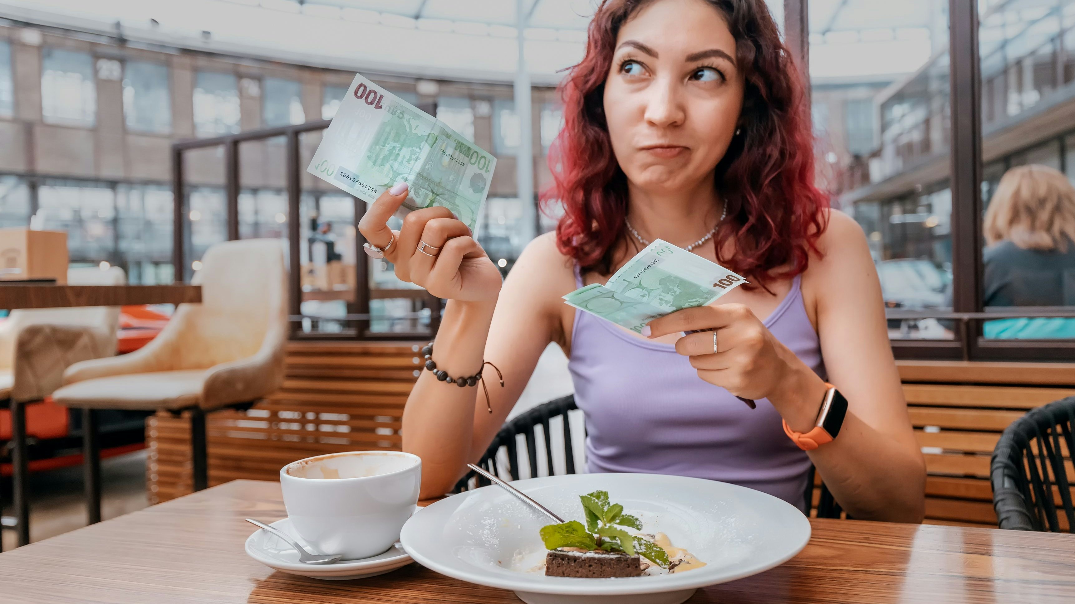 A frustrated girl pays for her dessert in a coffee shop with a euro bill. The concept of inflation and a sharp increase in prices