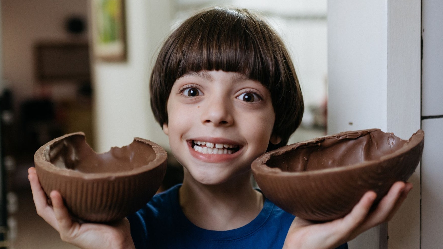 Boy holding two halves of an easter egg in the kitchen