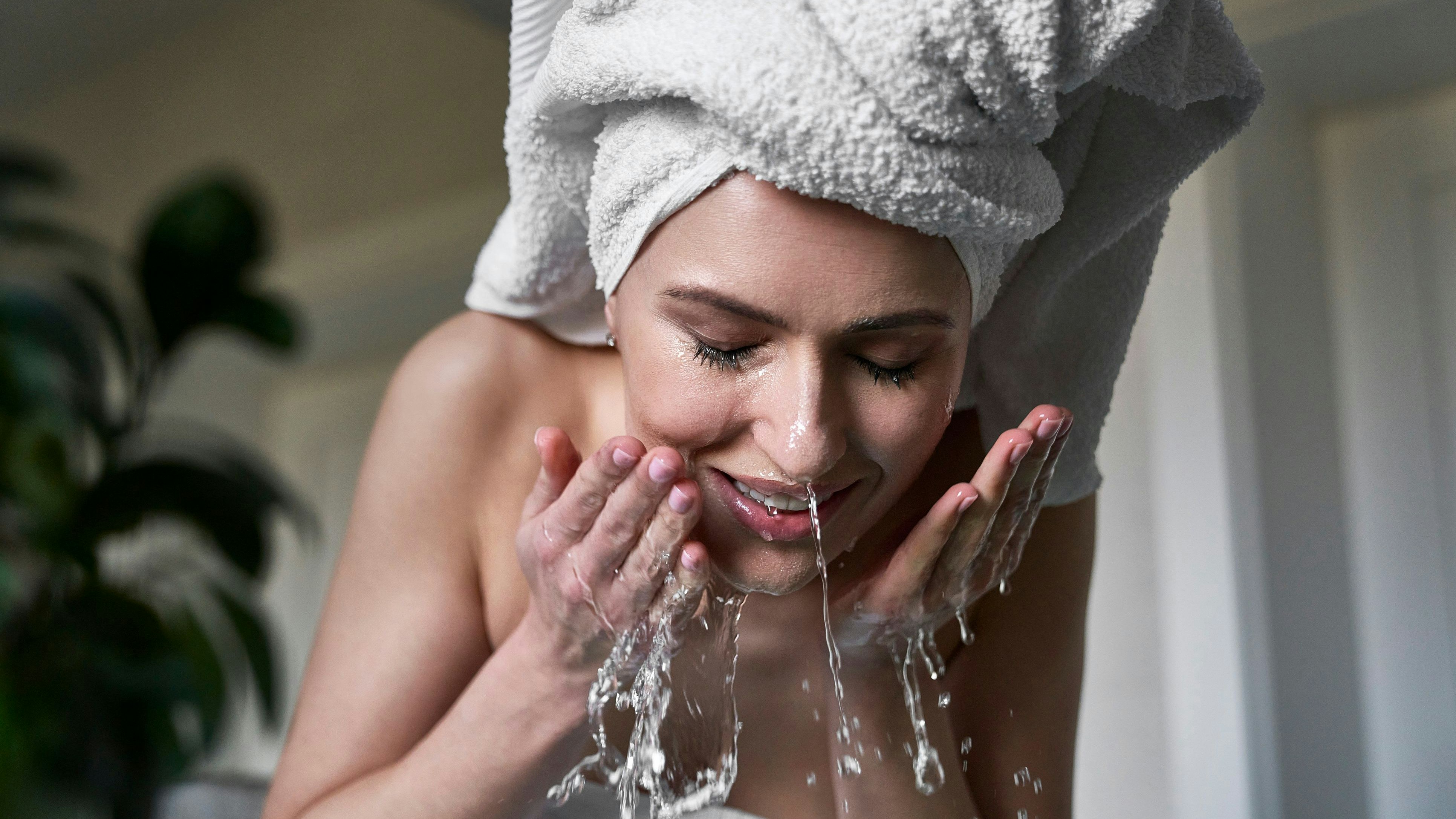 Front view of woman washing face with water in the bathroom