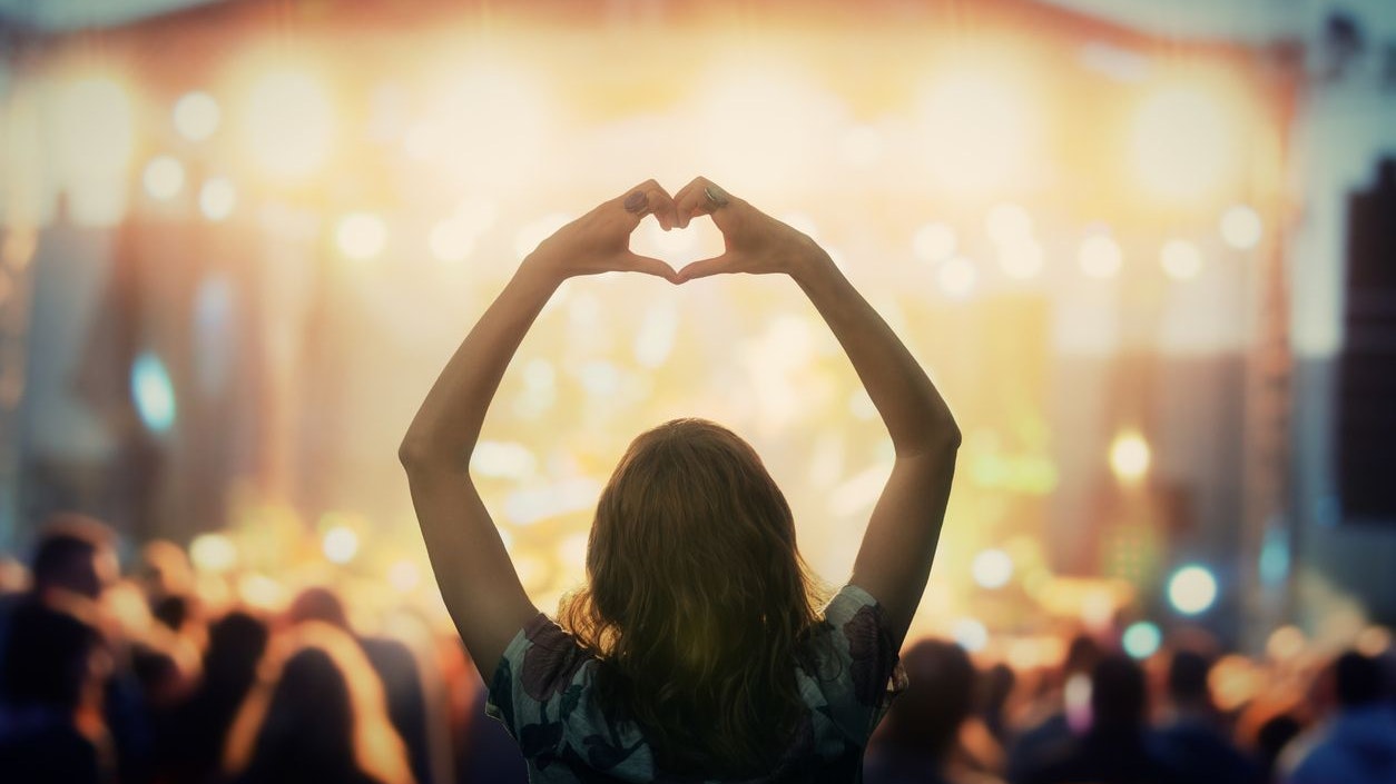 Girl making a heart-shape symbol for her favorite band.