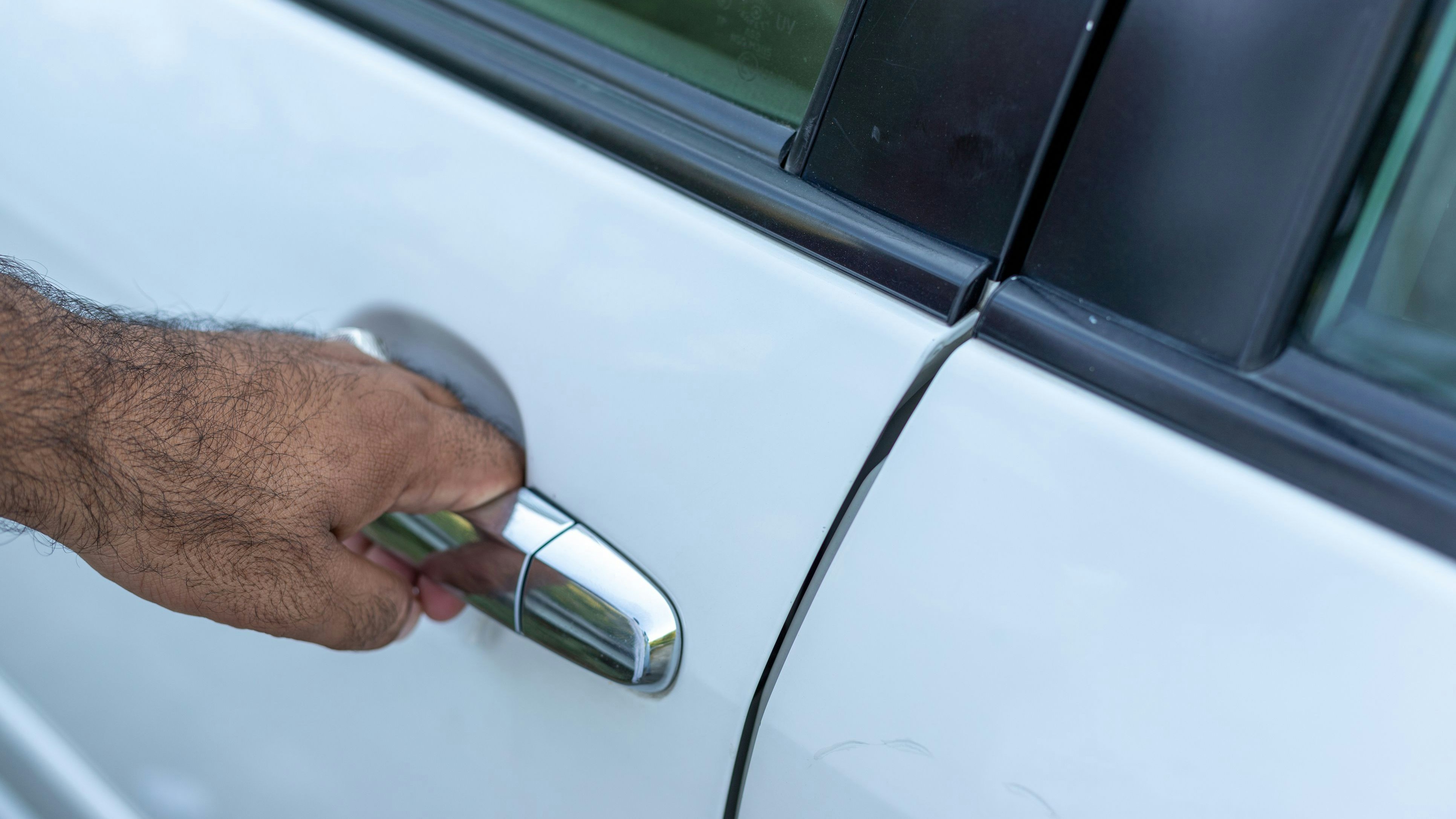Man holding a car door handle to open a car door