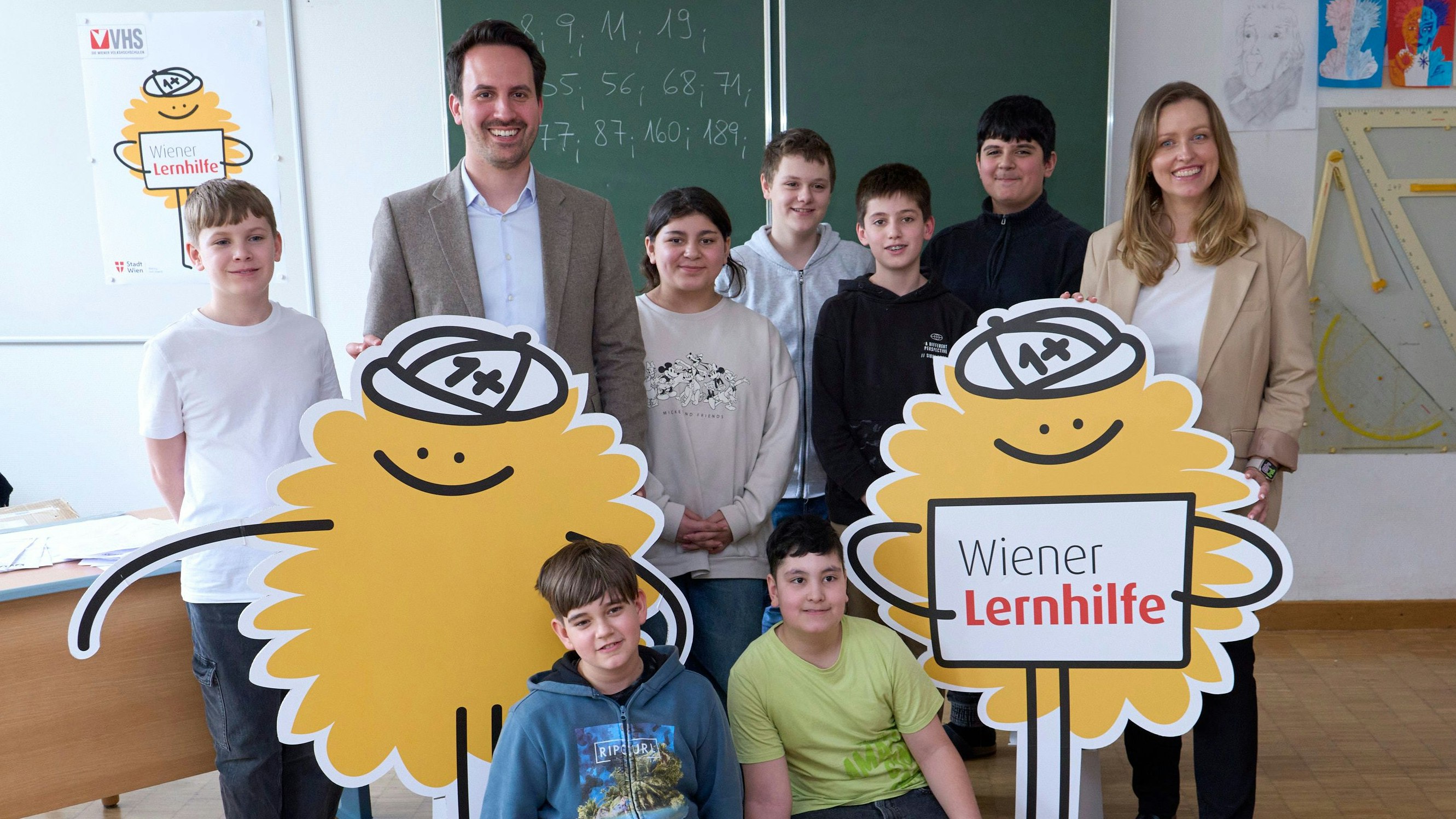 Vizebürgermeister Christoph Wiederkehr mit Schülern der Mittelschule Bendagasse (23. Bezirk), Daniela Ecker-Stepp, Leiterin des Geschäftsbereiches Schule der Wiener Volkshochschulen und das neue Maskottchen Eduard.