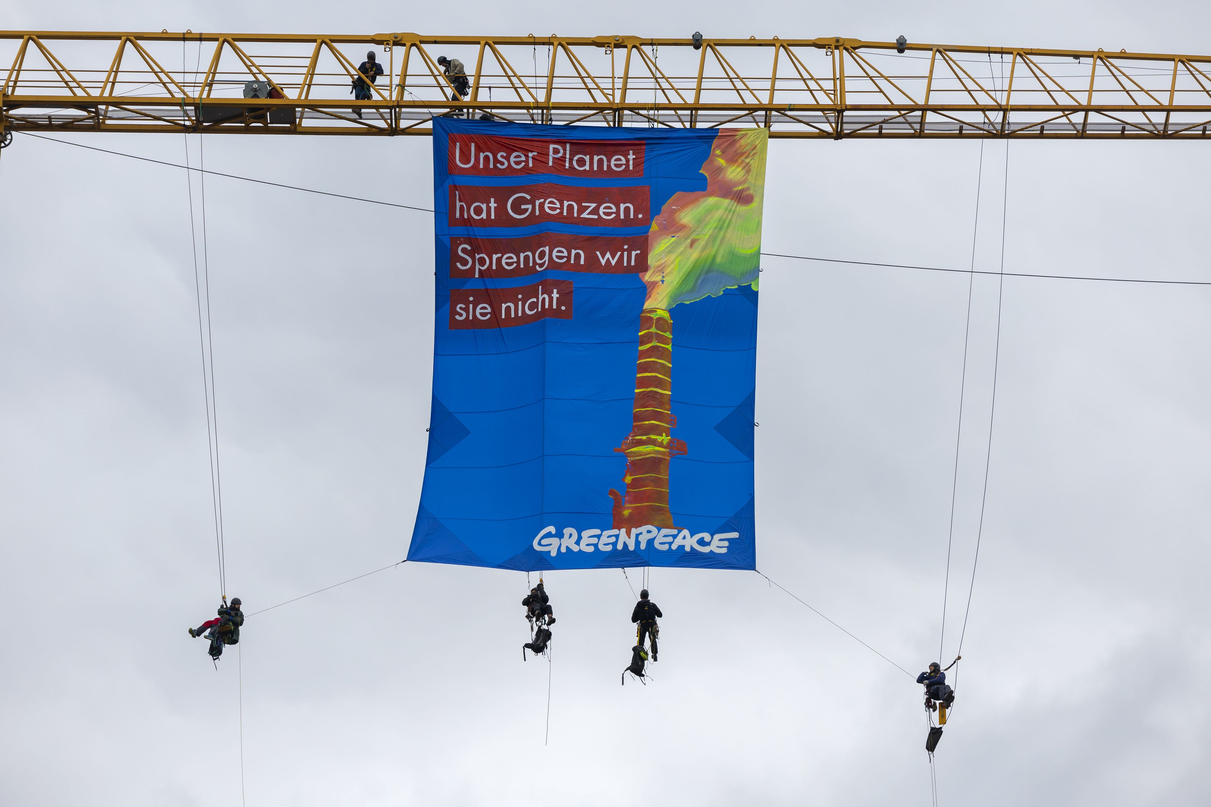 Greenpeace-Aktivisten entrollen auf einem Baukran ein Transparent mit der Aufschrift 