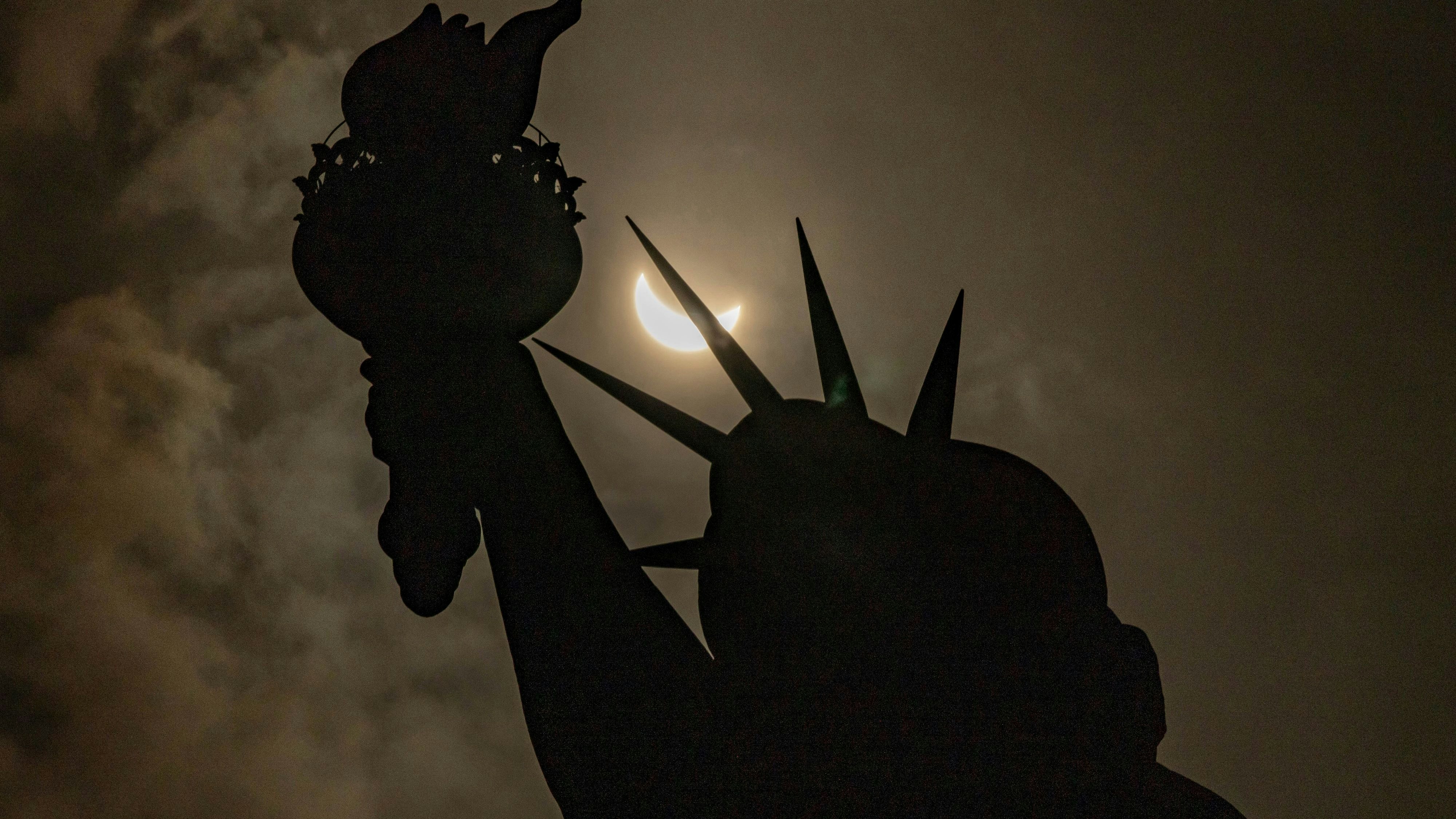 Hinter der Freiheitsstatue in New York verdunkelt sich der Himmel