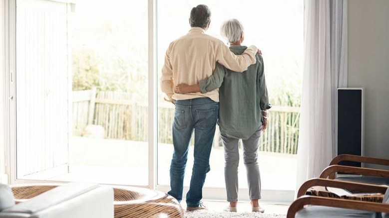 Rearview shot of an elderly couple looking out of their house together during a relaxing day at home