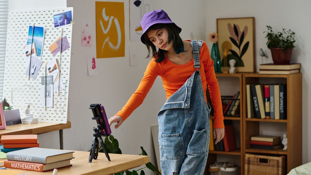 Teenage girl standing in front of smartphone and connecting it for online broadcast