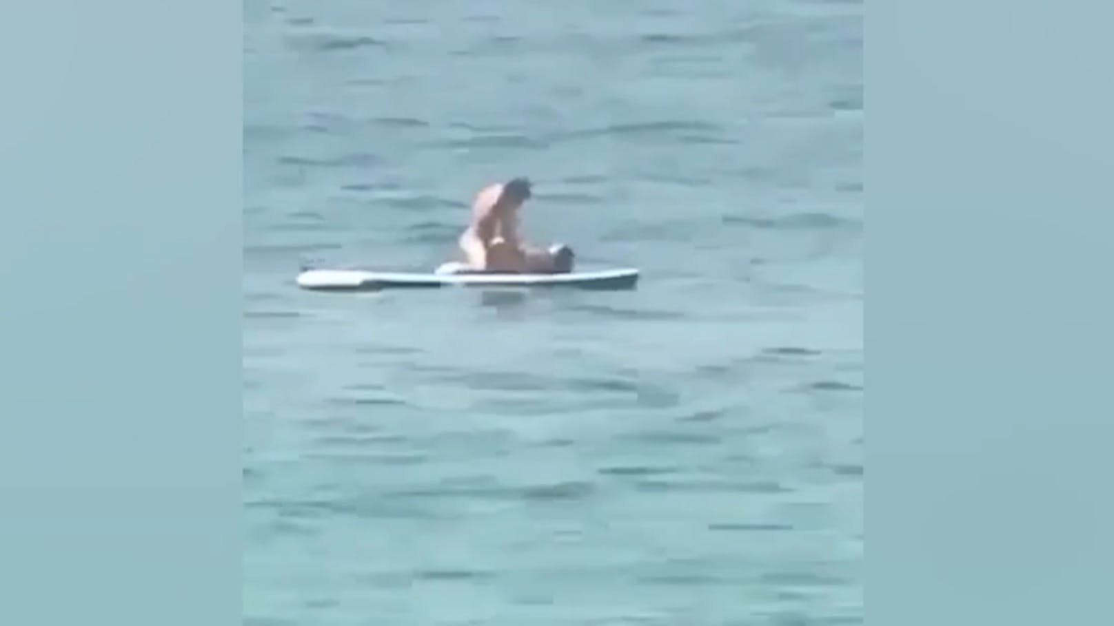 Paar treibt es vor Augen von Strandgästen im Meer
