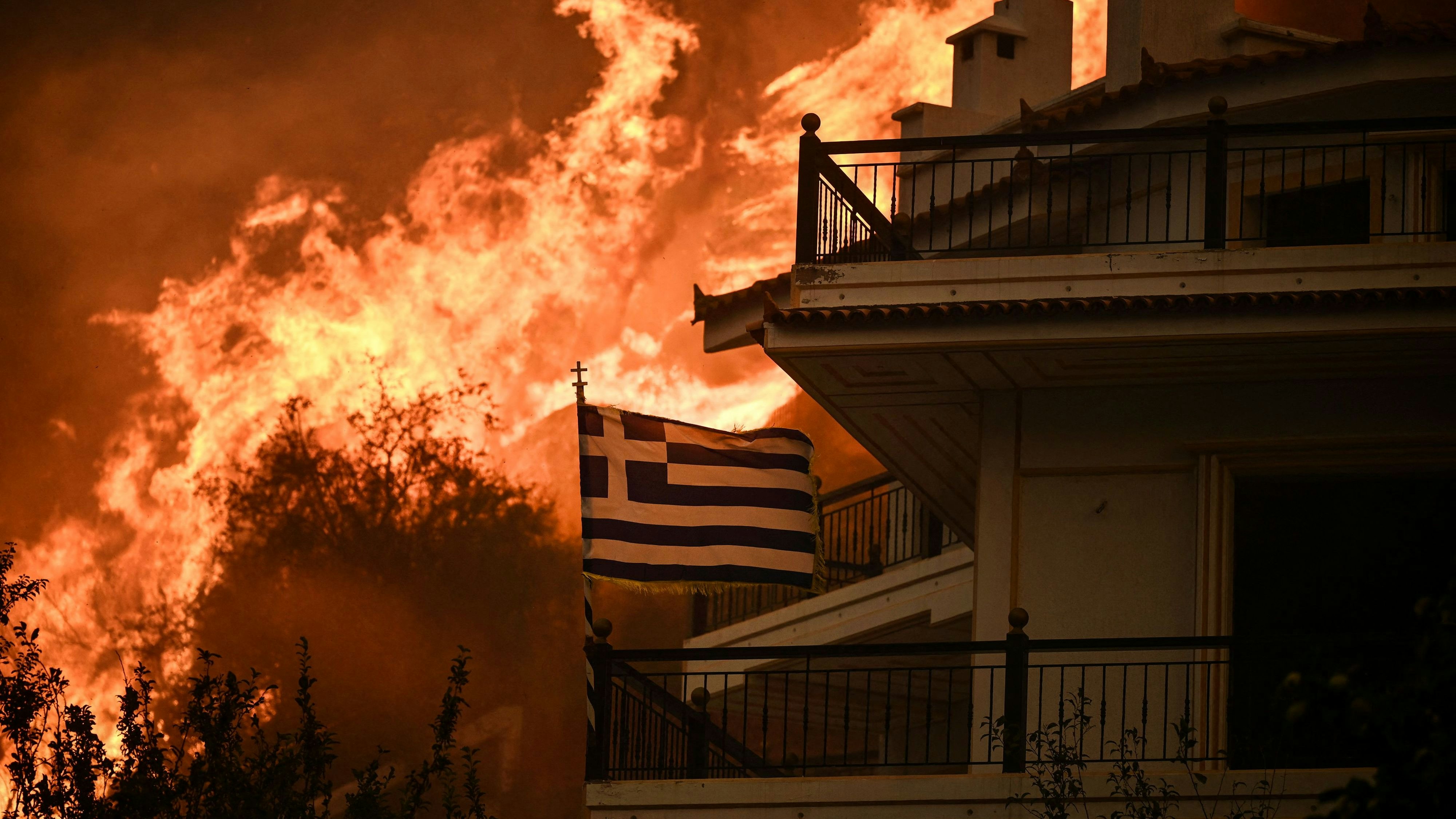 Download von www.picturedesk.com am 10.04.2024 (08:58).  TOPSHOT - A Greek flag flutters in the wind during a wildfire in Chasia in the outskirts of Athens on August 22, 2023. Greece's fire brigade on August 22, 2023 ordered the evacuation of a district on Athens' northwestern flank as firefighters battled a steadily growing wave of wildfires around the country, the second in a month. Tens of thousands of people have been urged to leave the district of Ano Liosia, while at the neighbouring community of Fyli an AFP journalist saw homes on fire. (Photo by Angelos Tzortzinis / AFP) - 20230822_PD12443 - Rechteinfo: Rights Managed (RM) Nur für redaktionelle Nutzung! Werbliche Nutzung erfordert Freigabe: bitte schicken Sie uns eine Anfrage.
