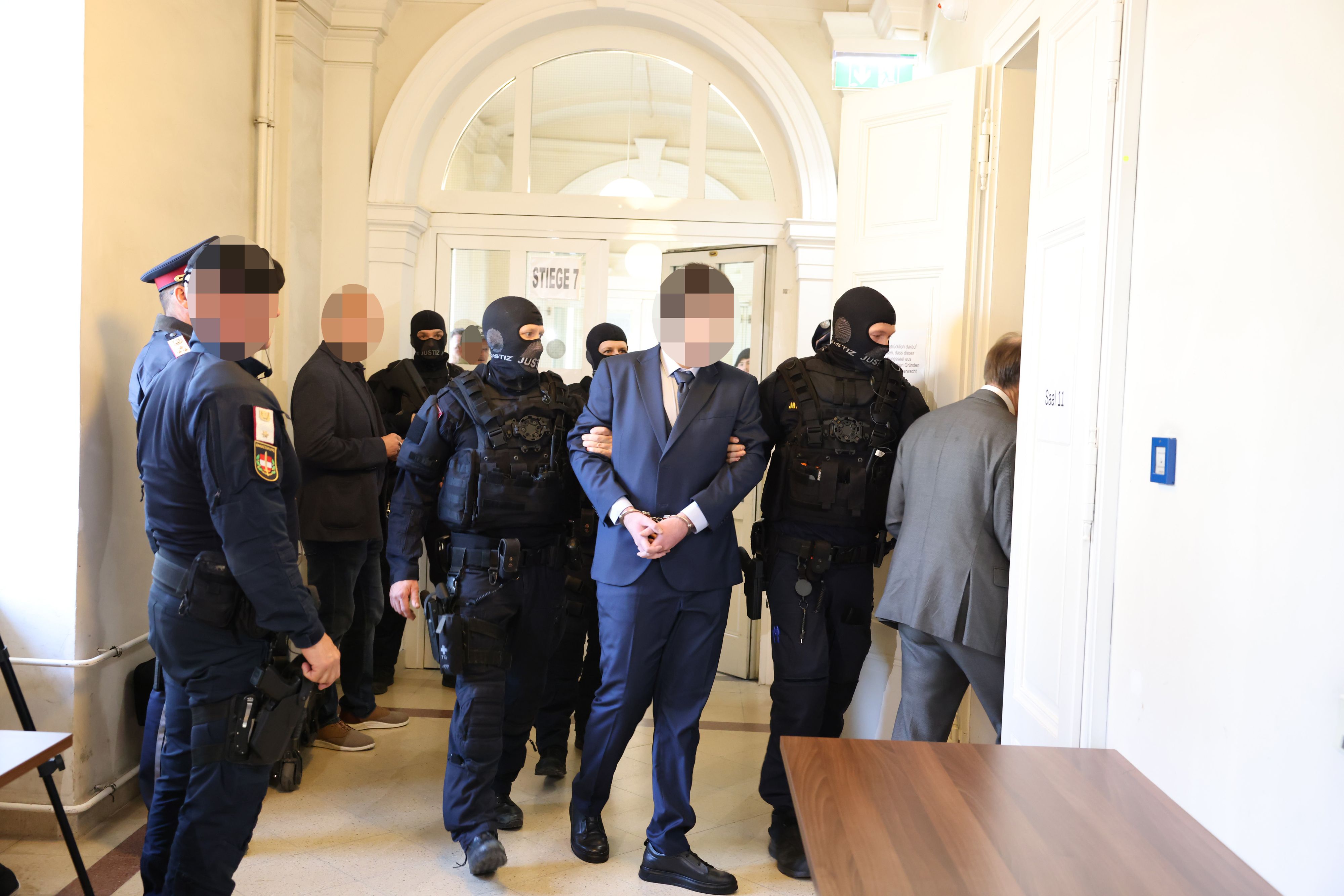 Der 17-Jährige wird von schwerbewaffneten Justizbeamten im dunkelblauen Sonntagsanzug vorgeführt.