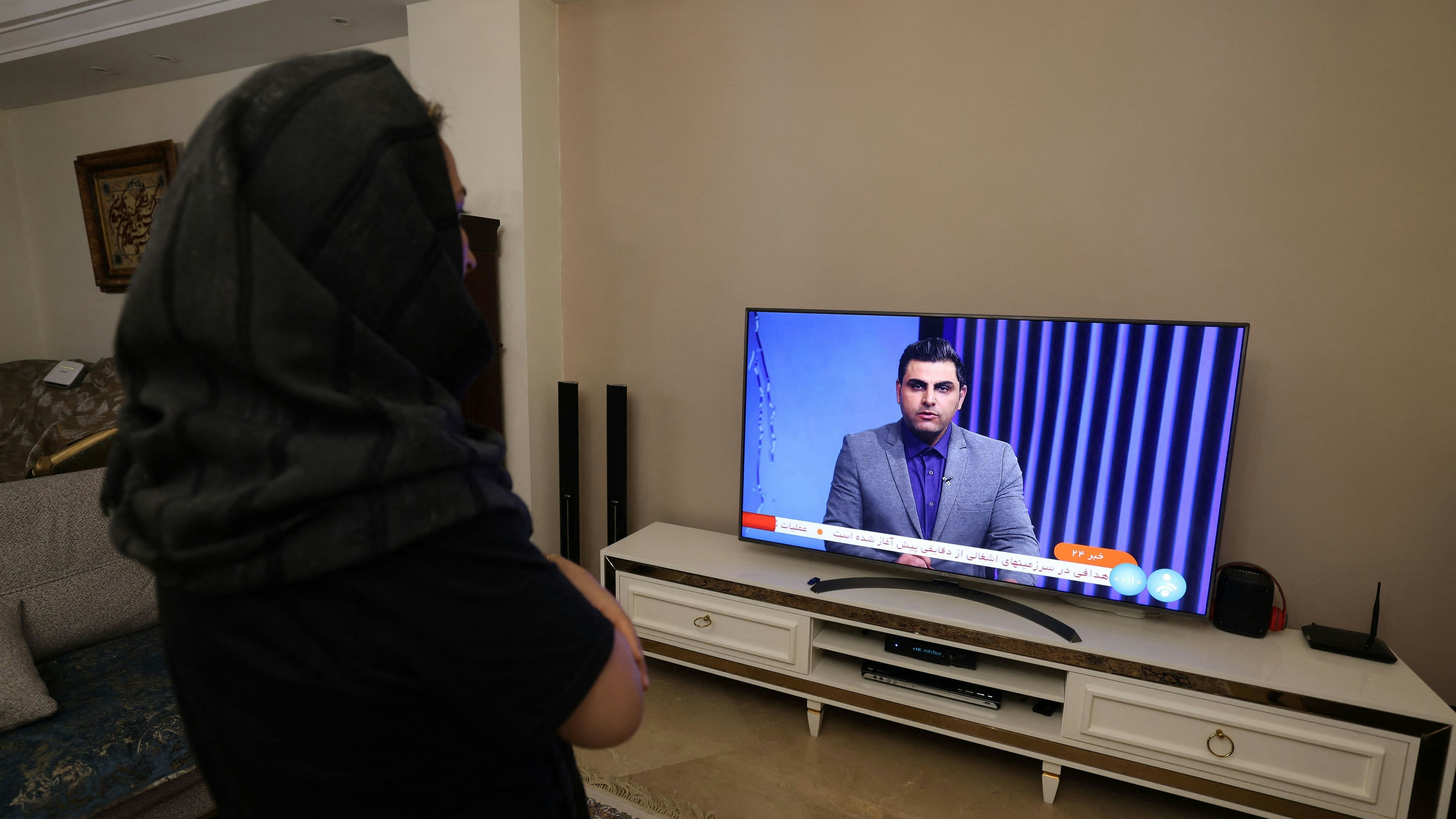 Eine iranische Frau schaut eine TV-Sendung an, in der über den iranischen Angriff auf Israel berichtet wird 