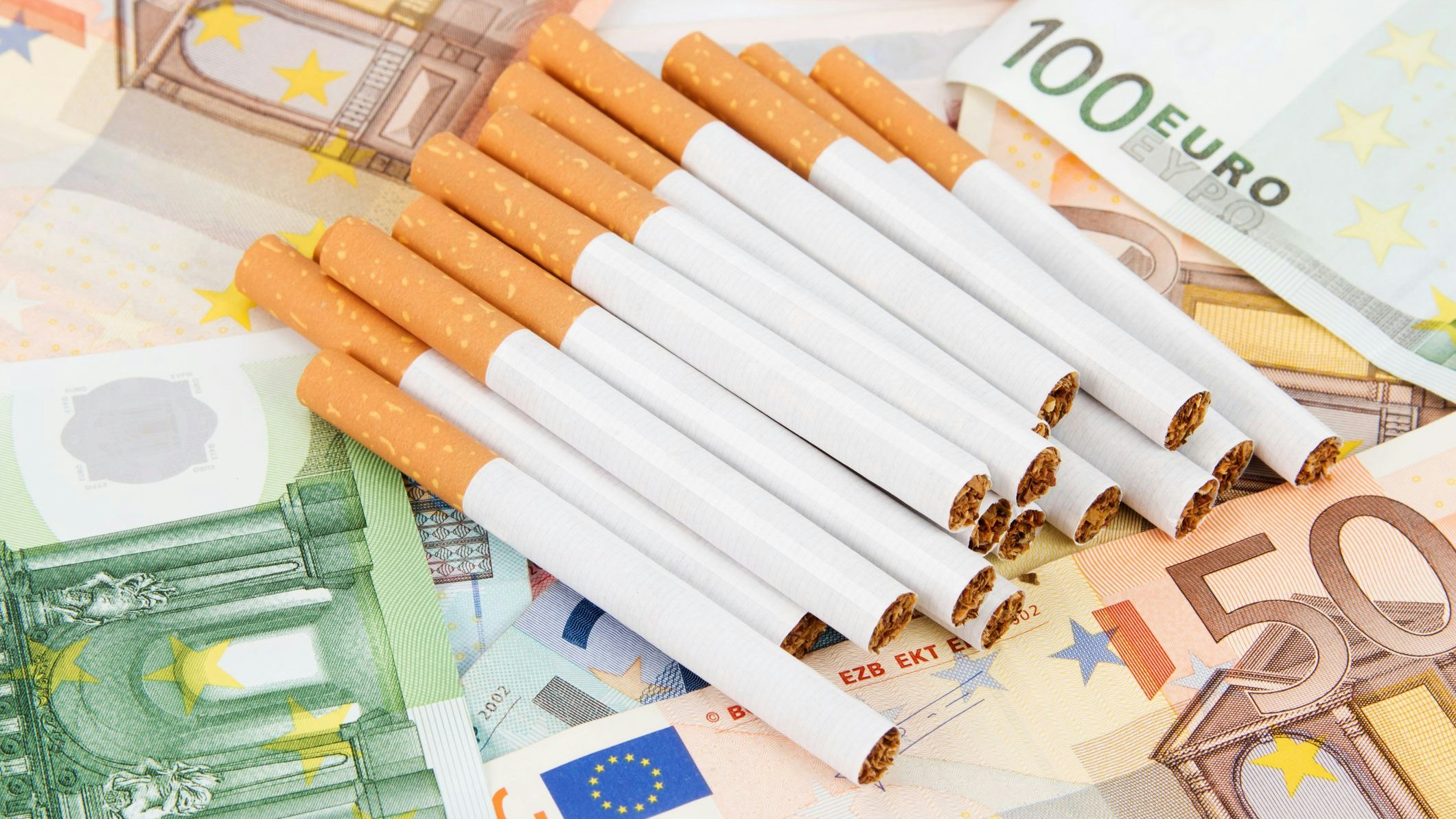 A lot of different Euro banknotes with a stack of cigarettes