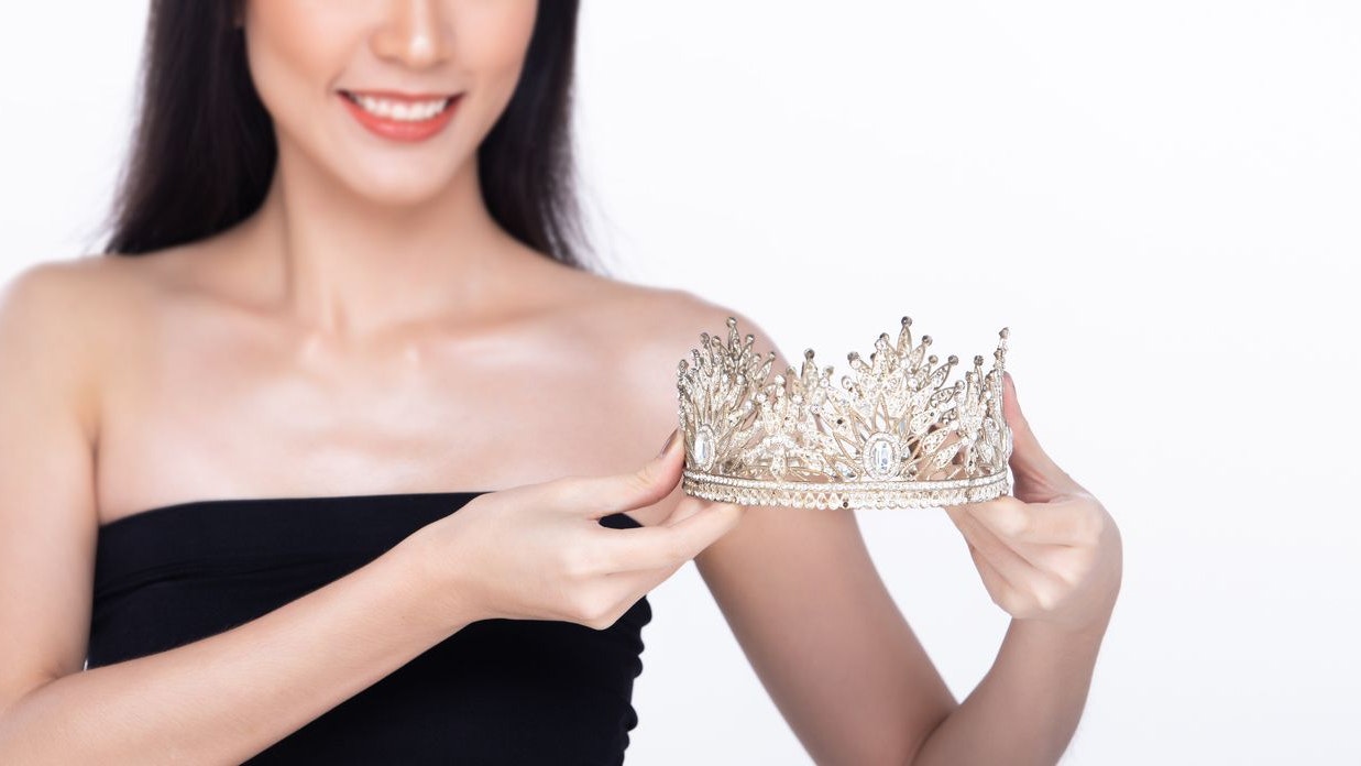 Beautiful fresh skin women hold Diamond Miss Beauty Pageant Contest Crown and long black hair. Portrait young girls in attractive natural fashion face express feel smile, isolated white background
