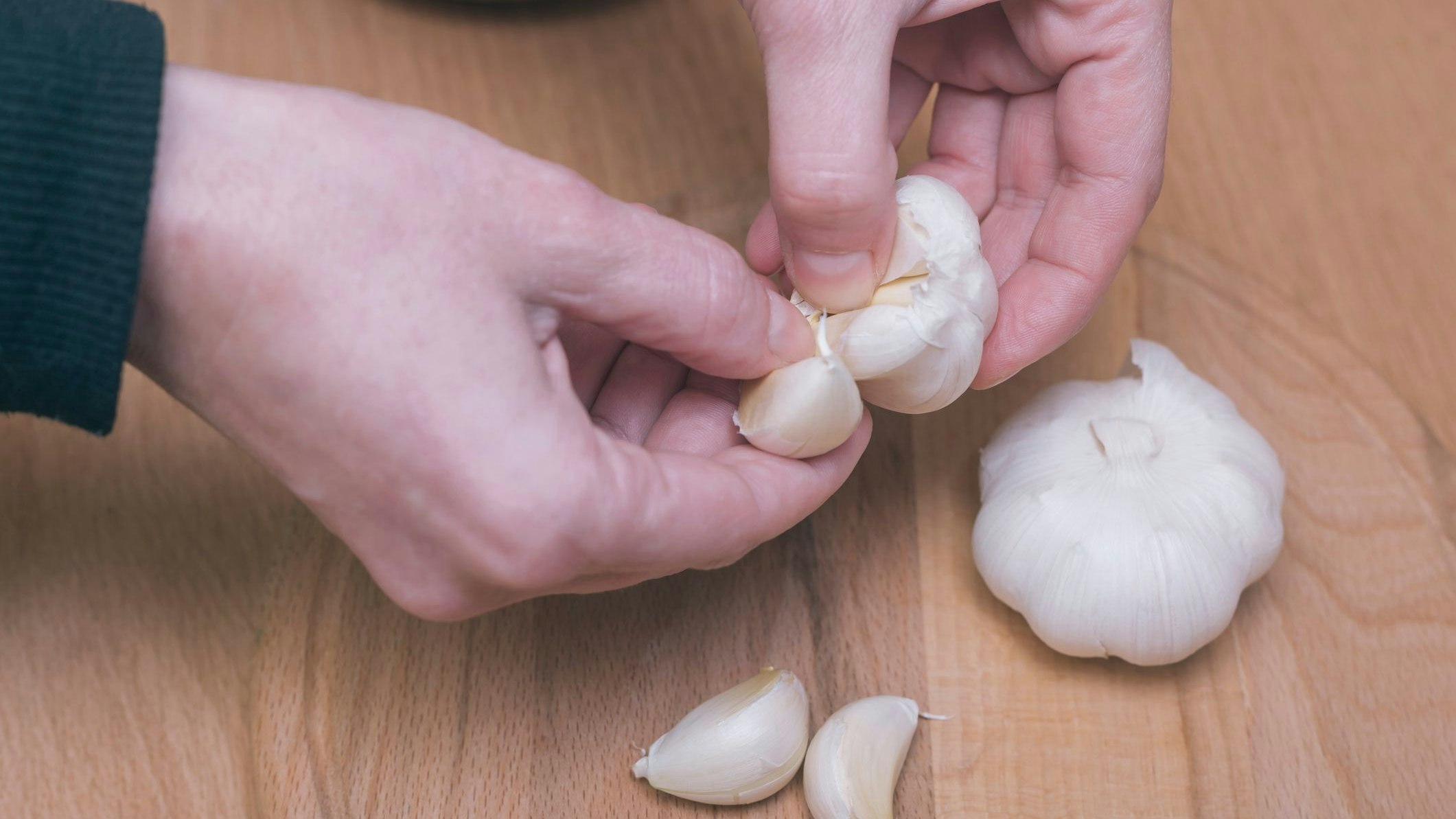 Female is preparing garlic for eat. Peeling.