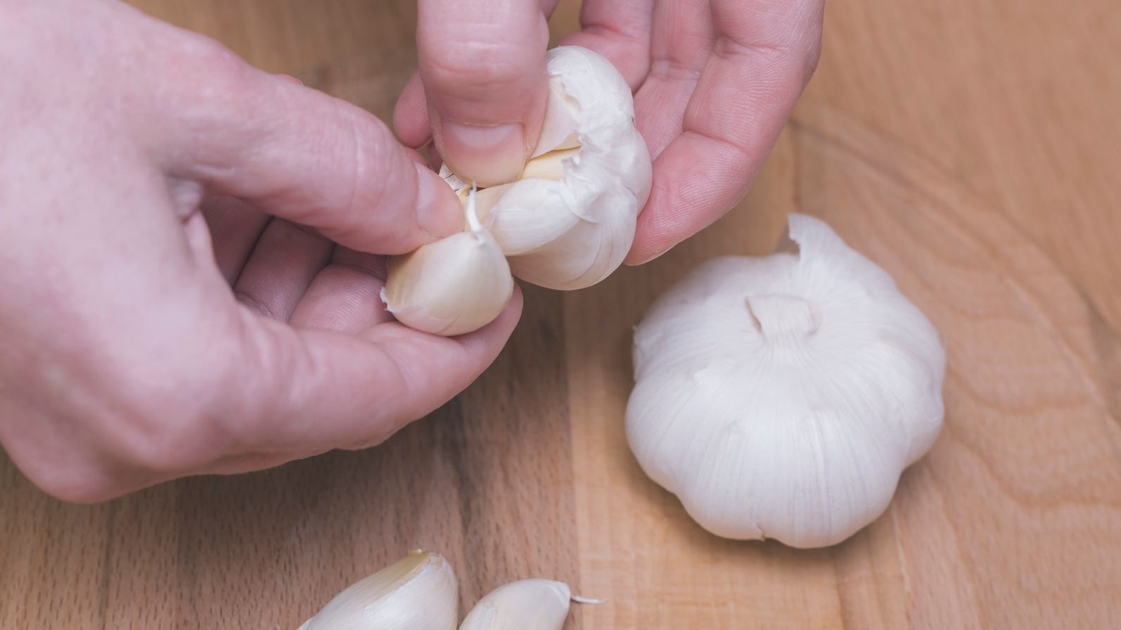 Female is preparing garlic for eat. Peeling.
