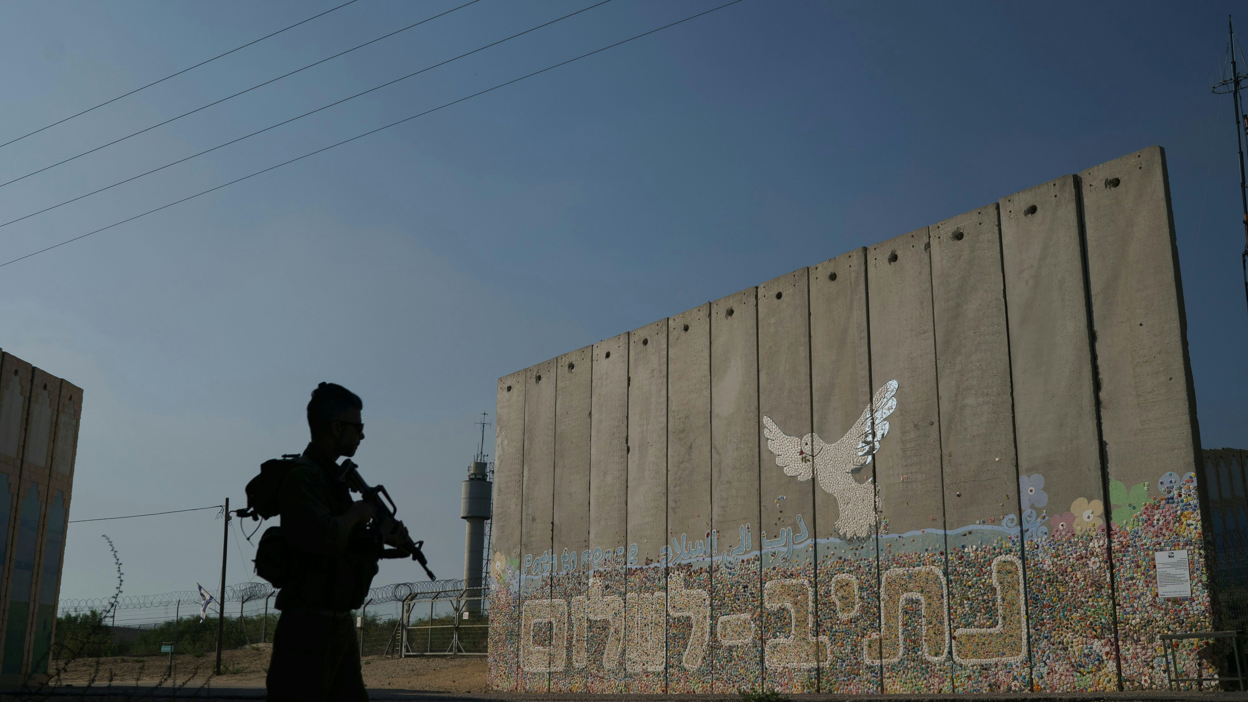 Download von www.picturedesk.com am 04.05.2024 (09:27).  A member of Israeli forces stands next to a security wall written in Hebrew "Path to Peace" at the kibbutz Netiv Haasara near the border with Gaza Strip, Israel, Friday, Nov. 17, 2023. The kibbutz, located close to the Gaza Strip's separation fence with Israel, was attacked during the Hamas cross-border attack on Oct. 7, killing members of its community. (AP Photo/Leo Correa) - 20231117_PD5315 - Rechteinfo: Rights Managed (RM)