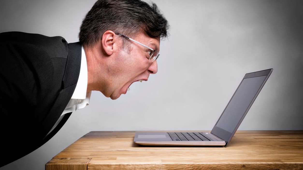 Man sitting at the table and screaming at his laptop