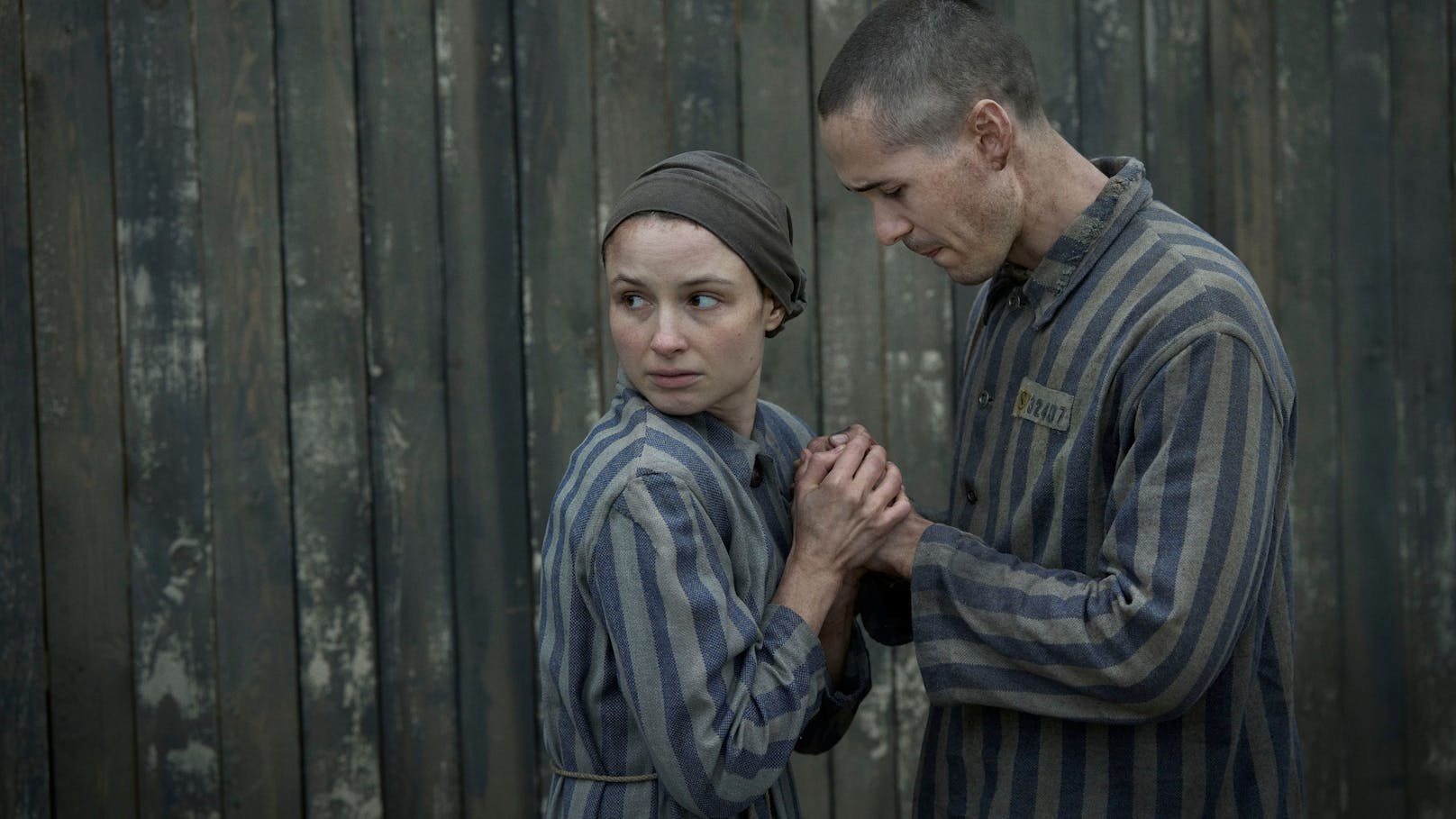 Jonah Hauer-King as Lali Sokolov seen here walking through Auschwitz with German-born actor Jonas Nay as Nazi officer Stefan Baretzki, front right