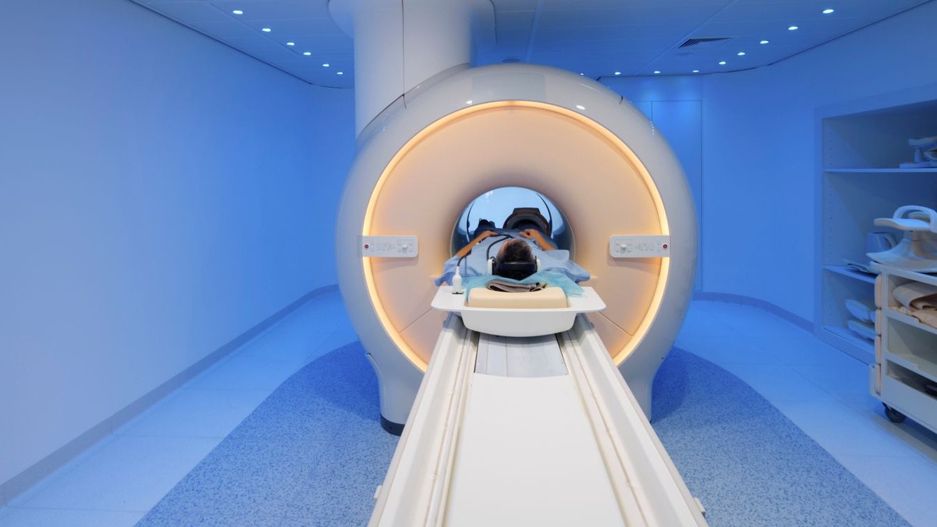 Senior male patient being slide into MRI scanner for knee scan.