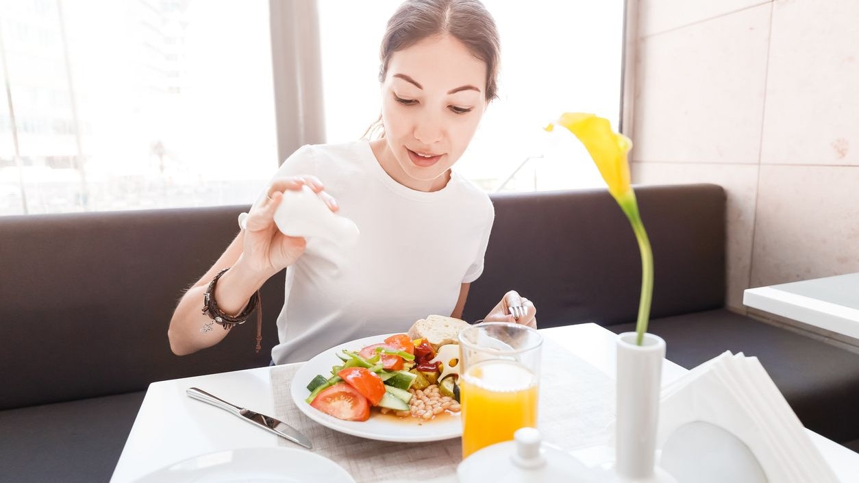Asian woman in casual clothes having continental breakfast in hotel restaurant