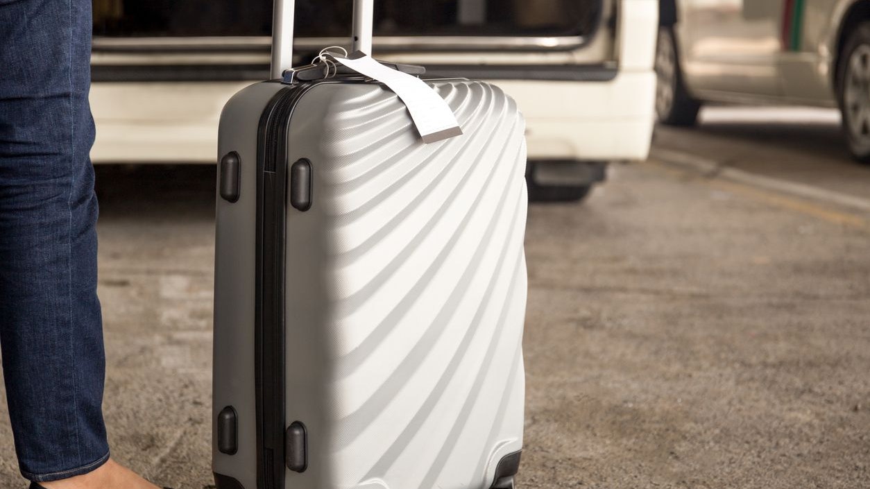 Woman tourist standing with luggage waiting for taxi at airport