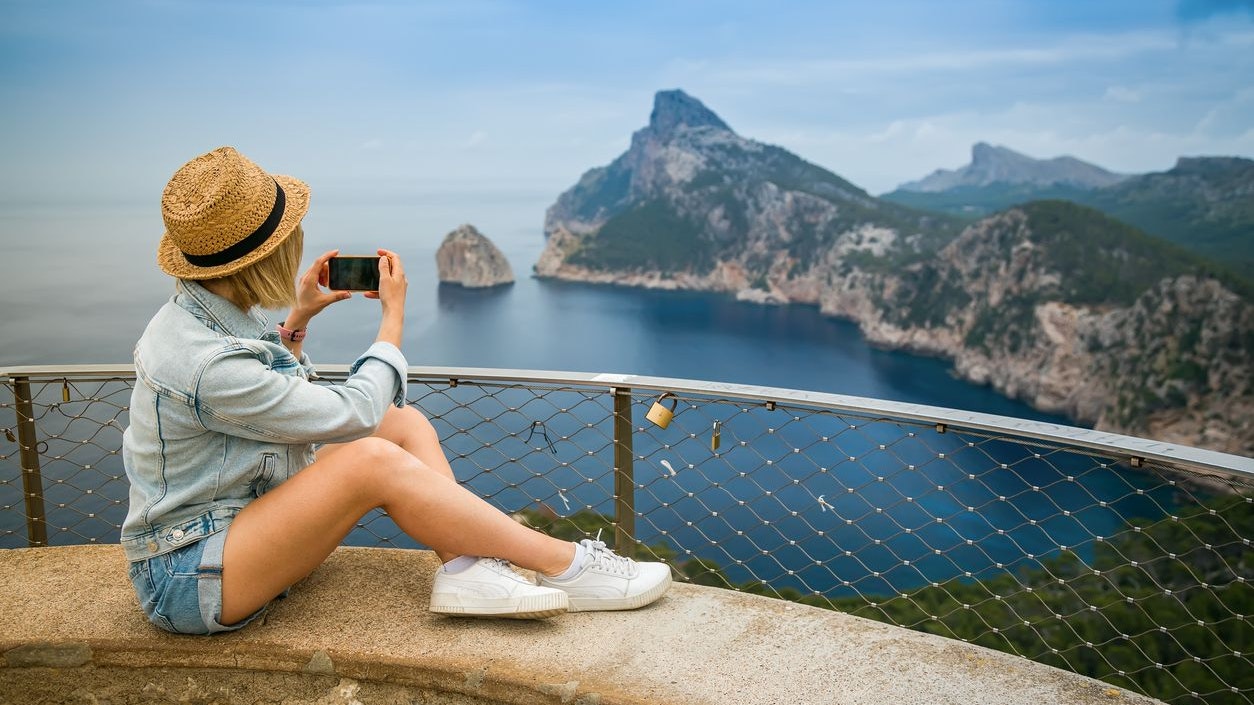 A tourist woman taking a picture on her mobile of Cap Formentor in Mallorca, Spain