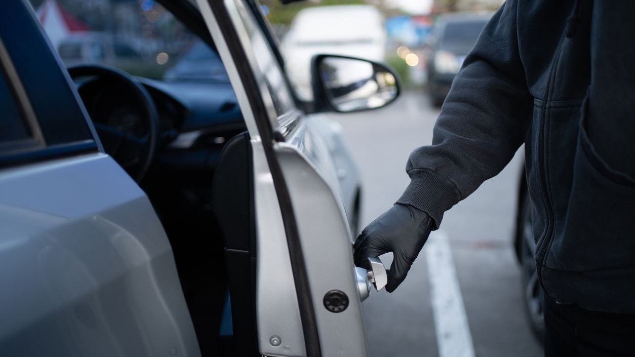 Close-up shot of a thief wearing a black shirt and black gloves. He tried to open the car door and tried to break in. car theft concept.